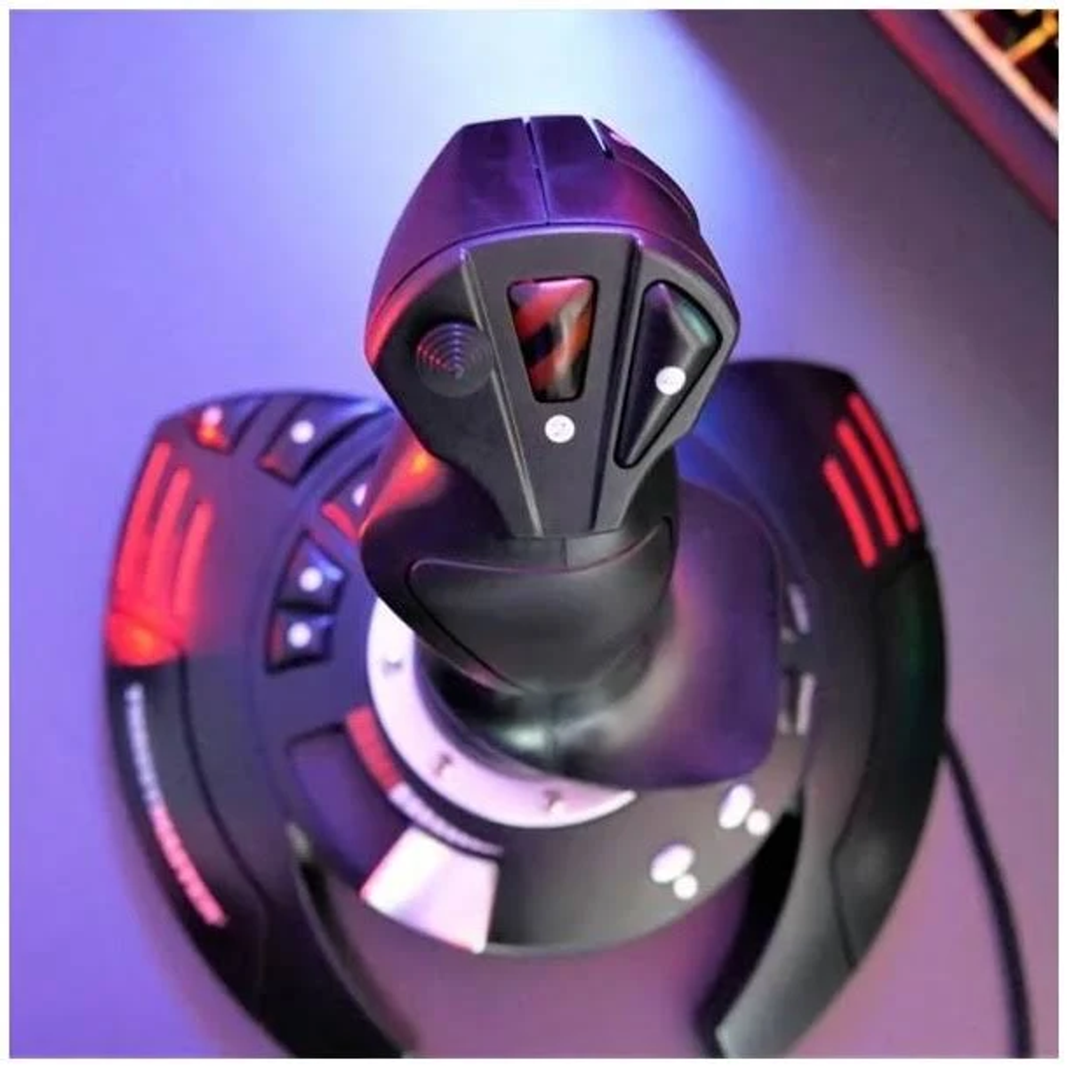 Een zwarte joystick met knoppen en rode lichten. Het staat op een paars oppervlak.