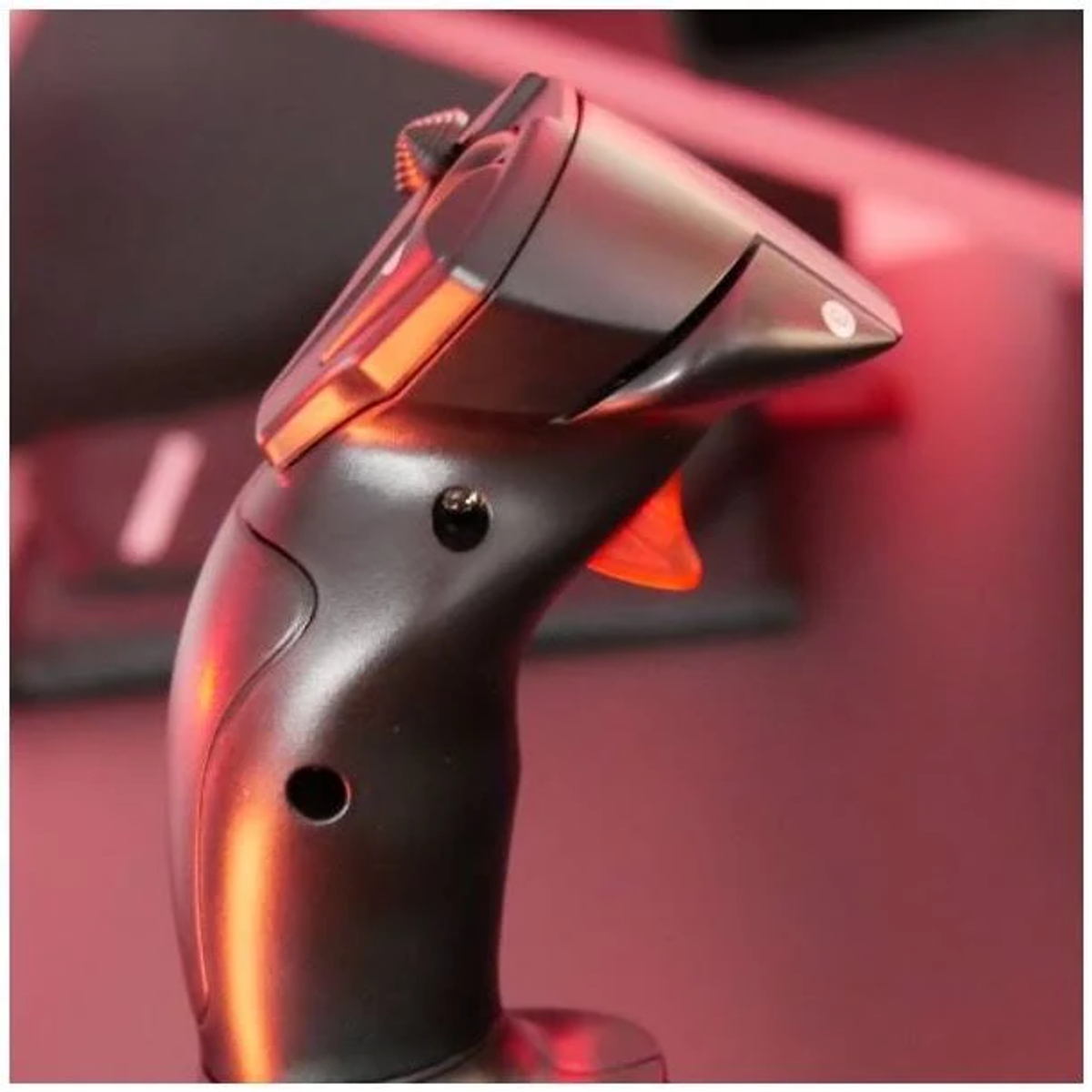 Zwarte joystick, met een rode knop. Close-up, met een donkerrode achtergrond en een lichtreflectie.