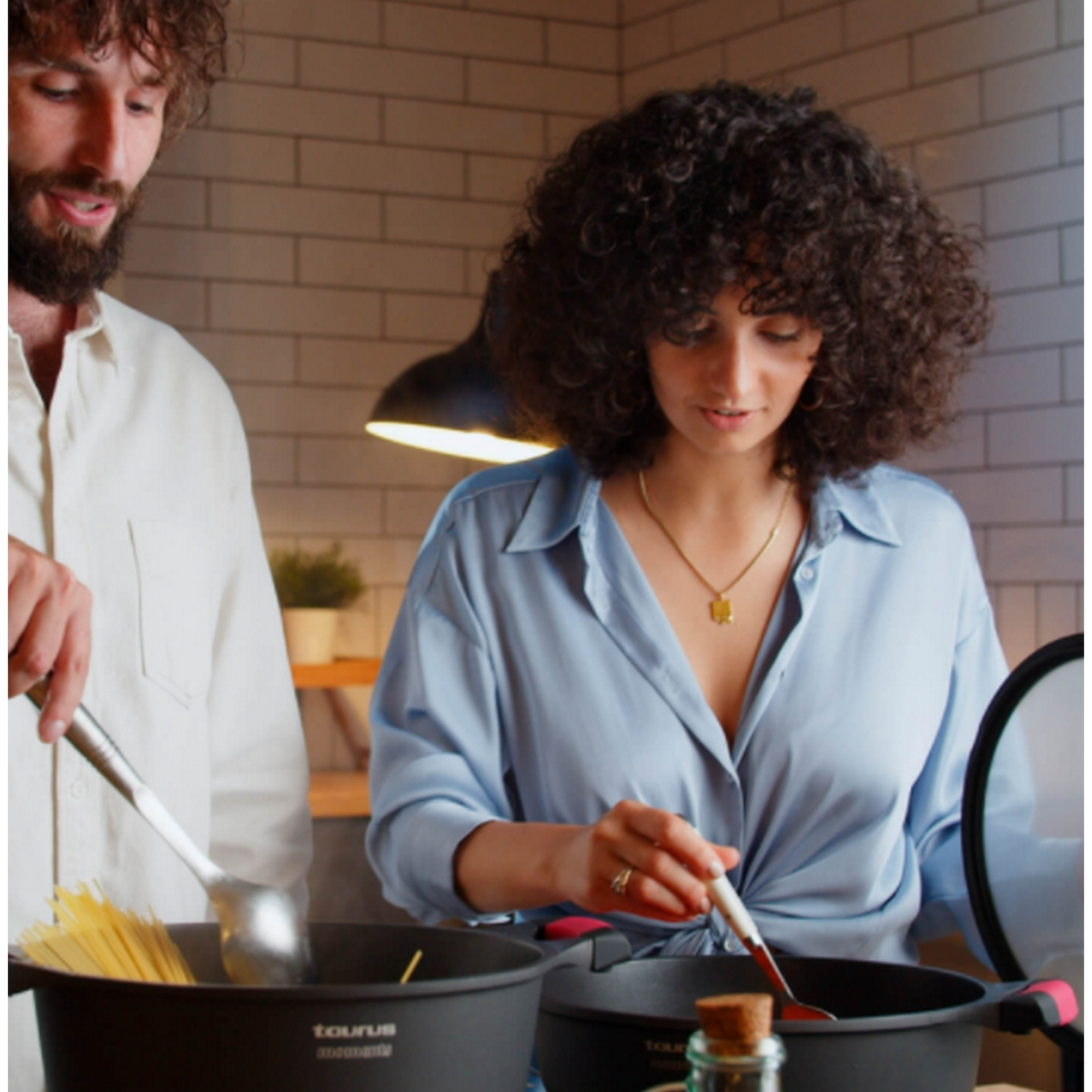 Ein Mann und eine Frau kochen. Die Frau rührt Essen in einem Topf um.