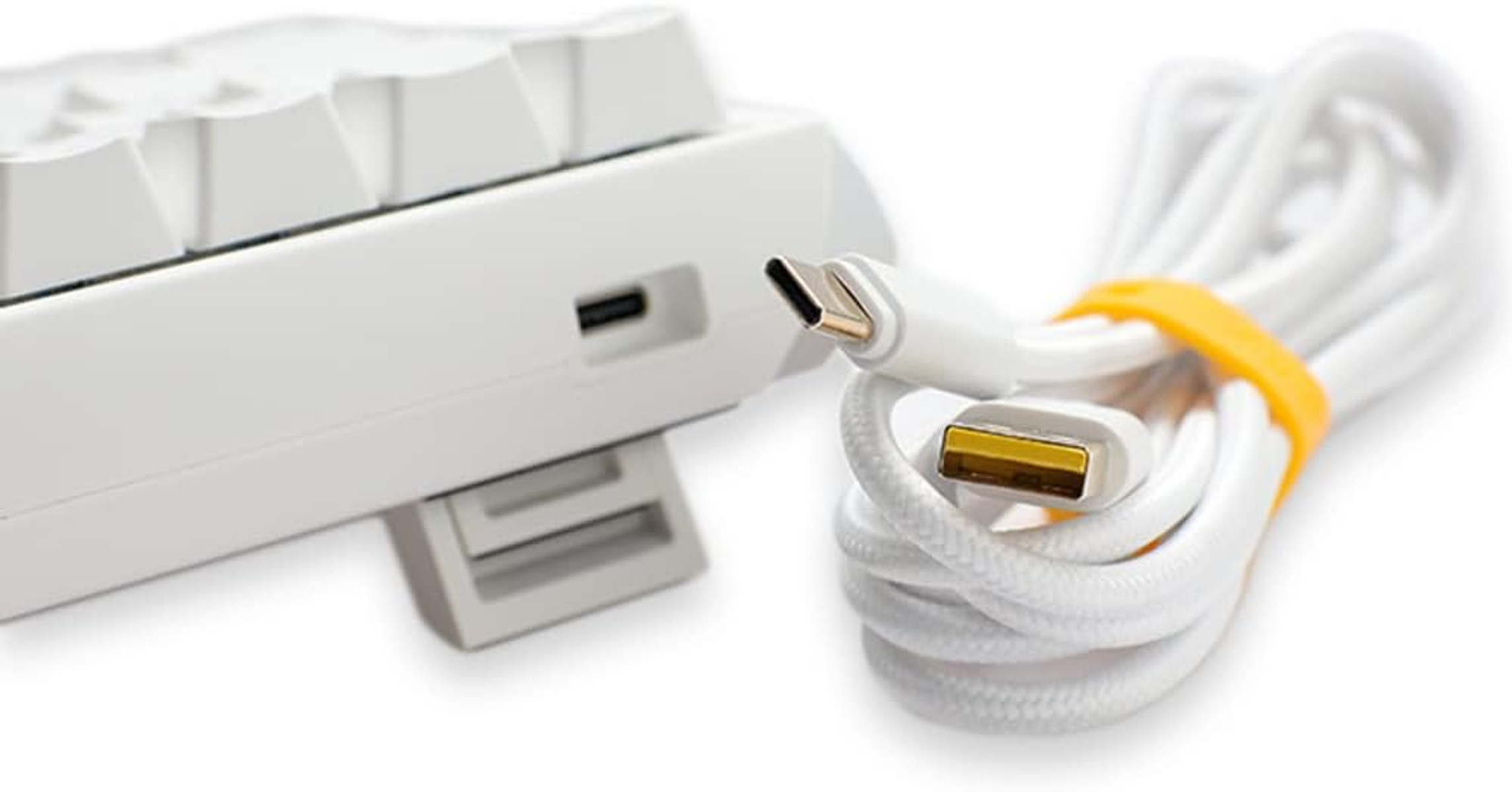 Wit toetsenbord met witte kabel en gele band, close-up op witte achtergrond.