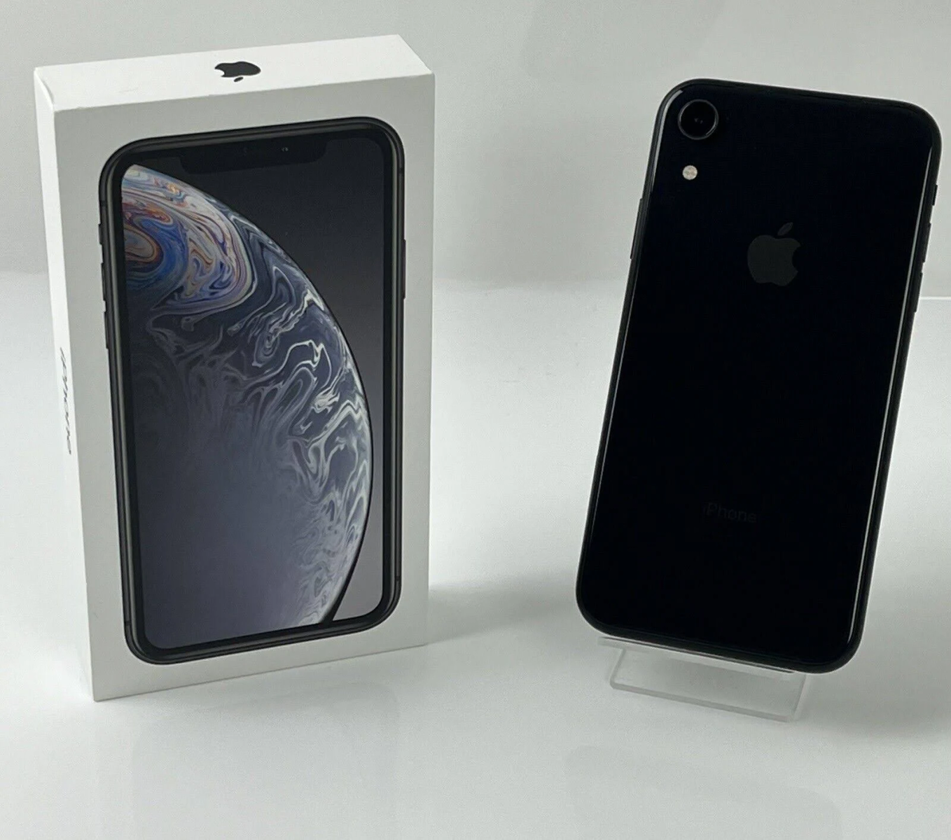 Schwarzes iPhone XR neben seiner weißen Box. Beide befinden sich auf einer weißen Oberfläche.