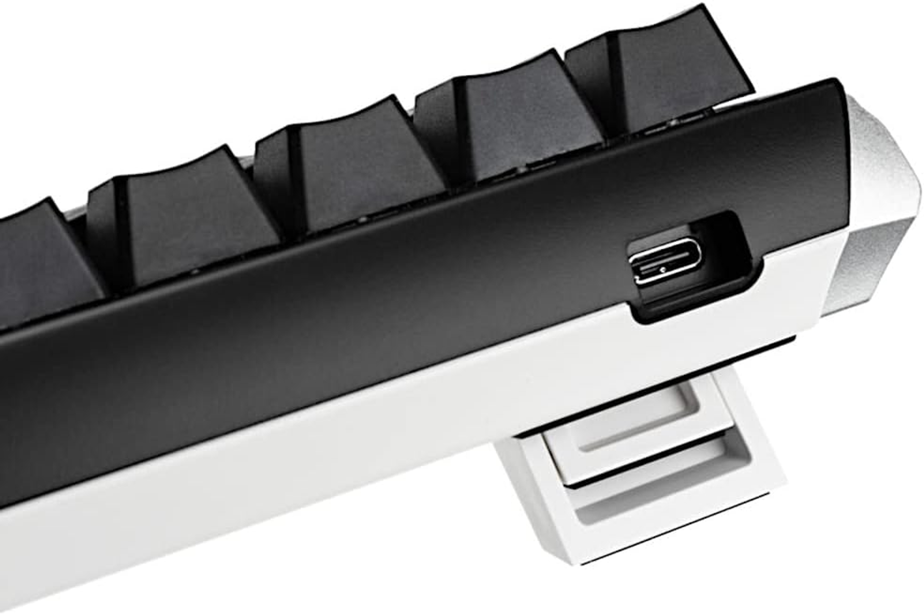 Primo piano di una tastiera bianca e nera con porta USB-C laterale. Tasti neri visibili.
