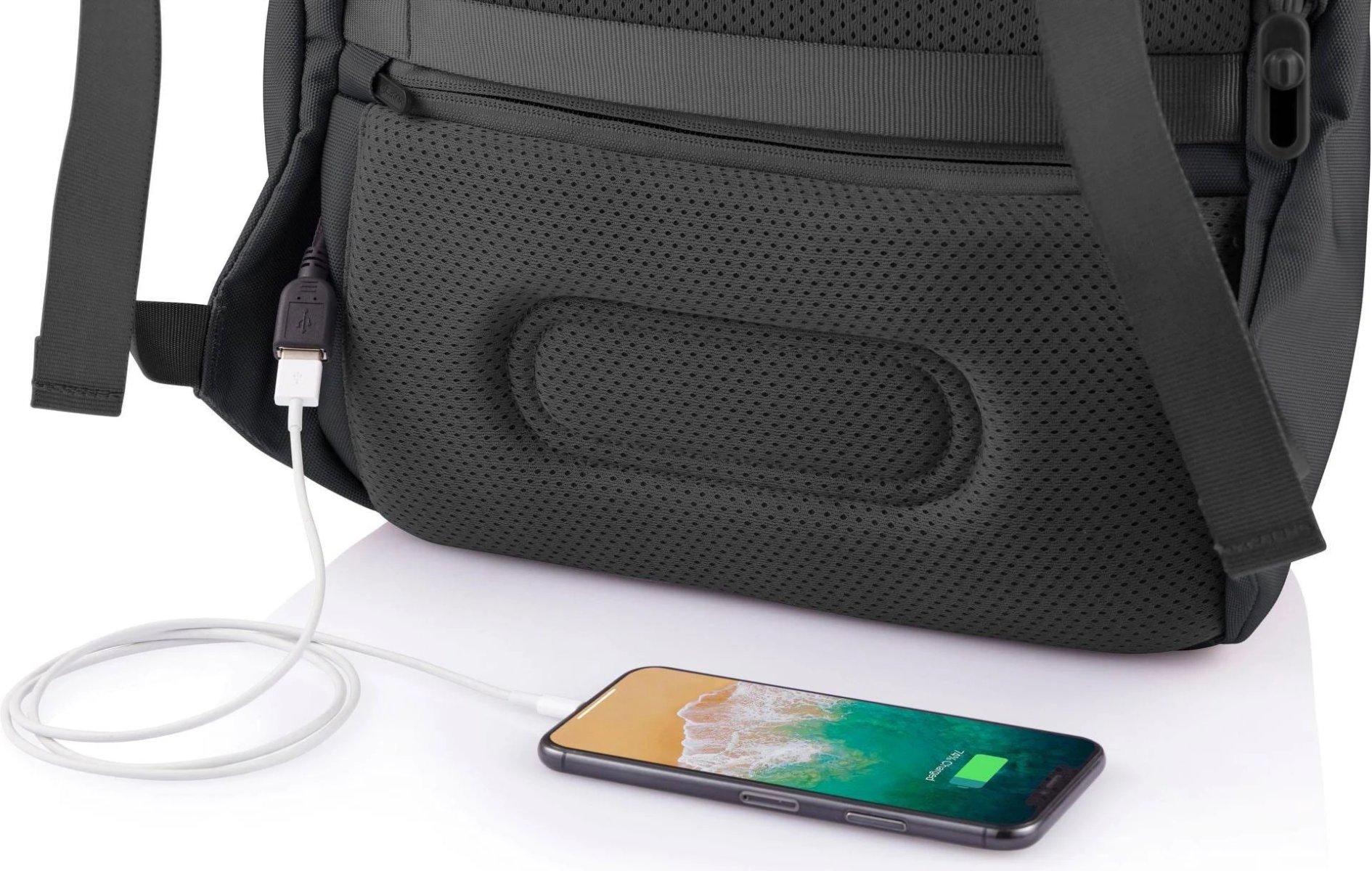 Schienale di uno zaino nero con cavo USB che carica un telefono. Il telefono mostra la carica.