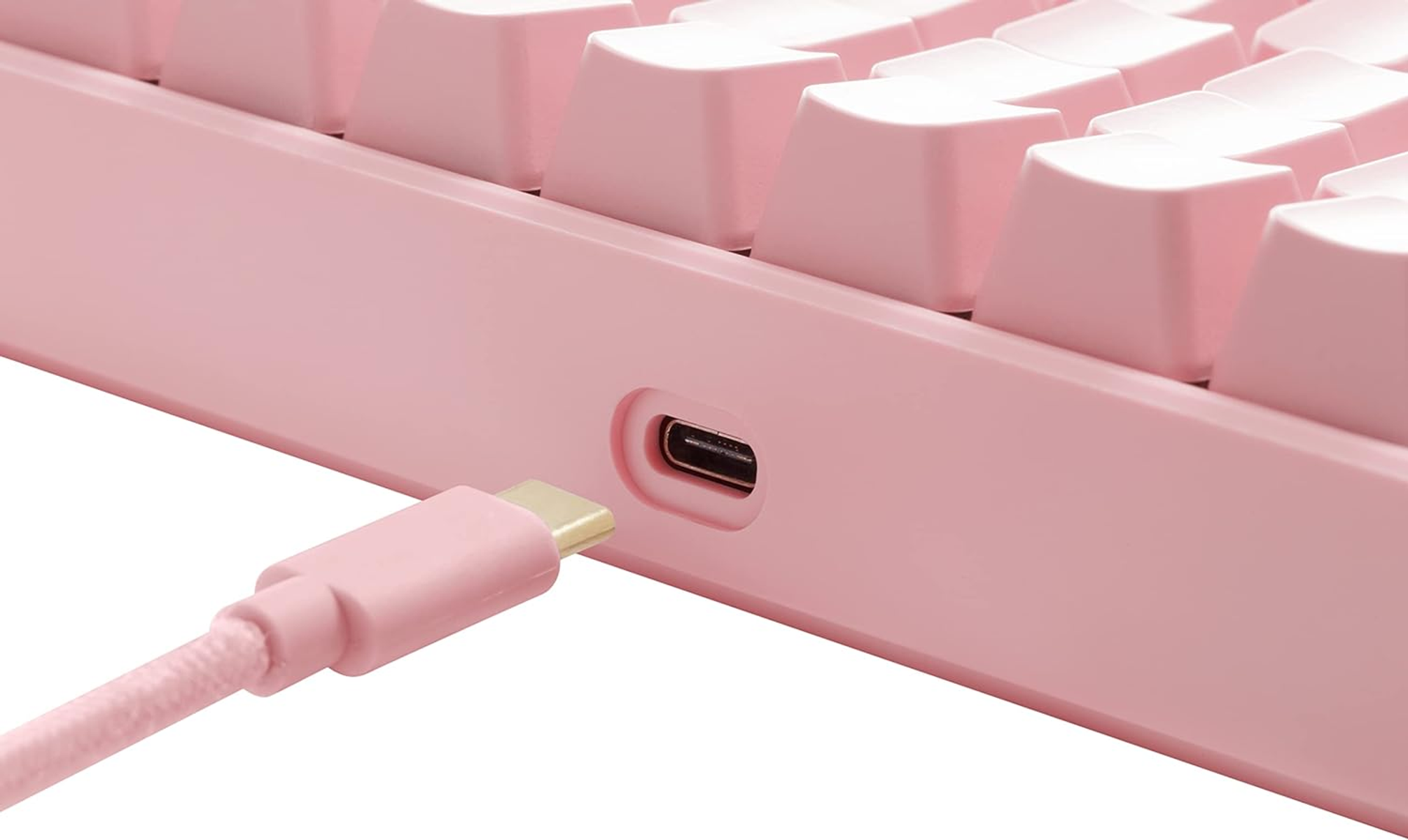 Rosa Tastatur mit USB-C-Anschluss und eingestecktem rosa Kabel, Nahaufnahme.
