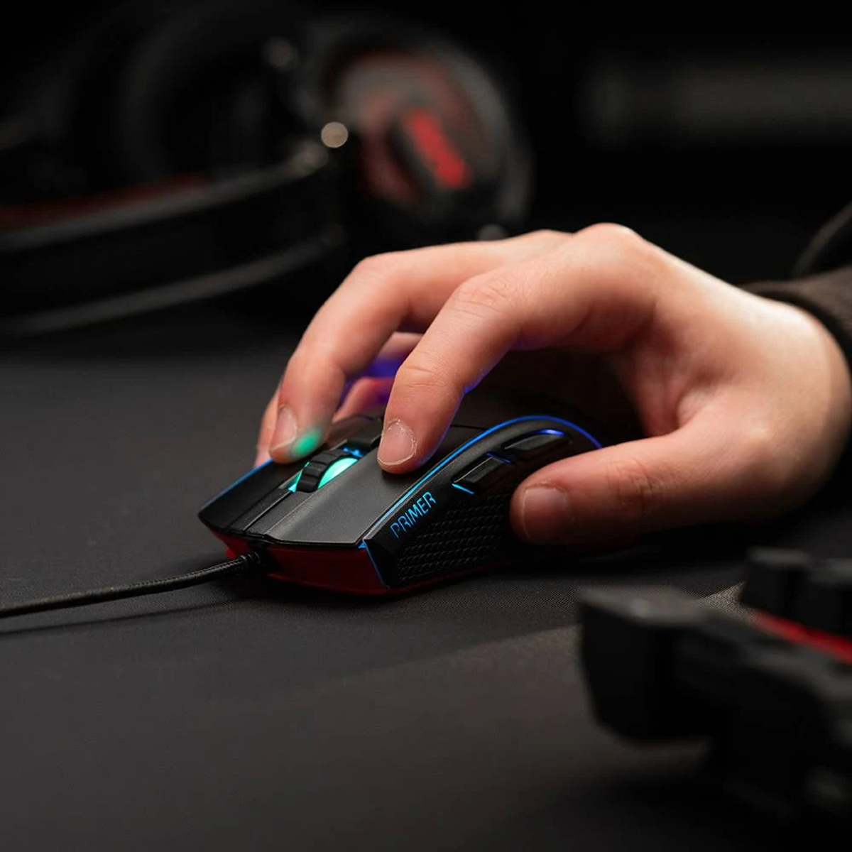 Mano che usa un mouse nero con accenti blu e rossi su una superficie nera.