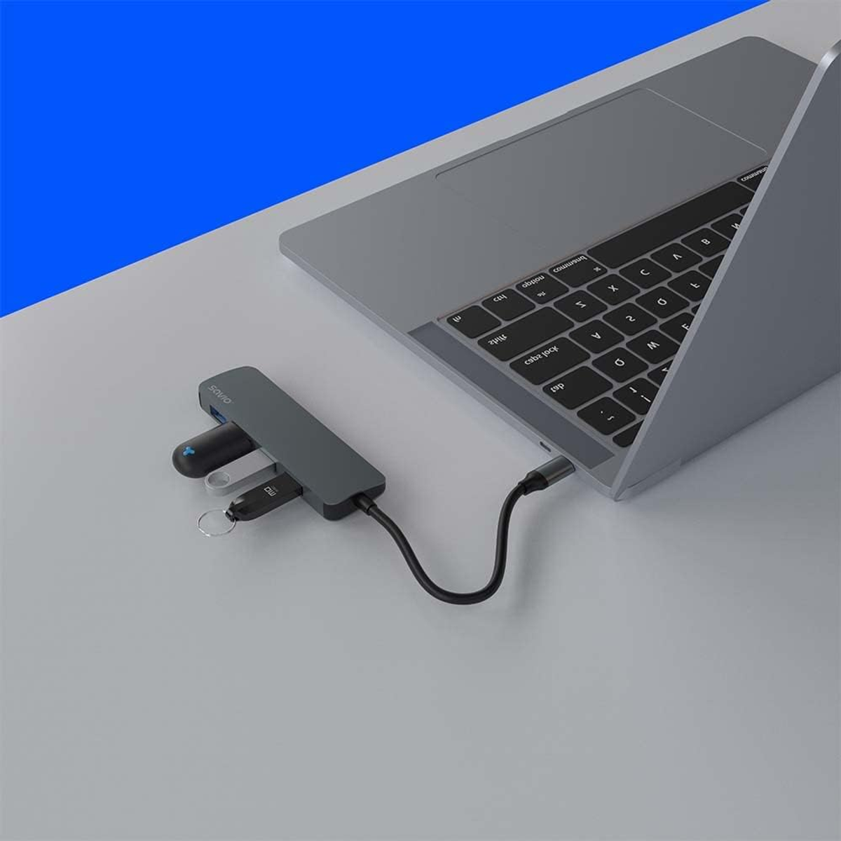 Ein USB-Hub, der mit einem Laptop verbunden ist, mit USB-Laufwerken und einem USB-C-Kabel auf weißer Oberfläche.