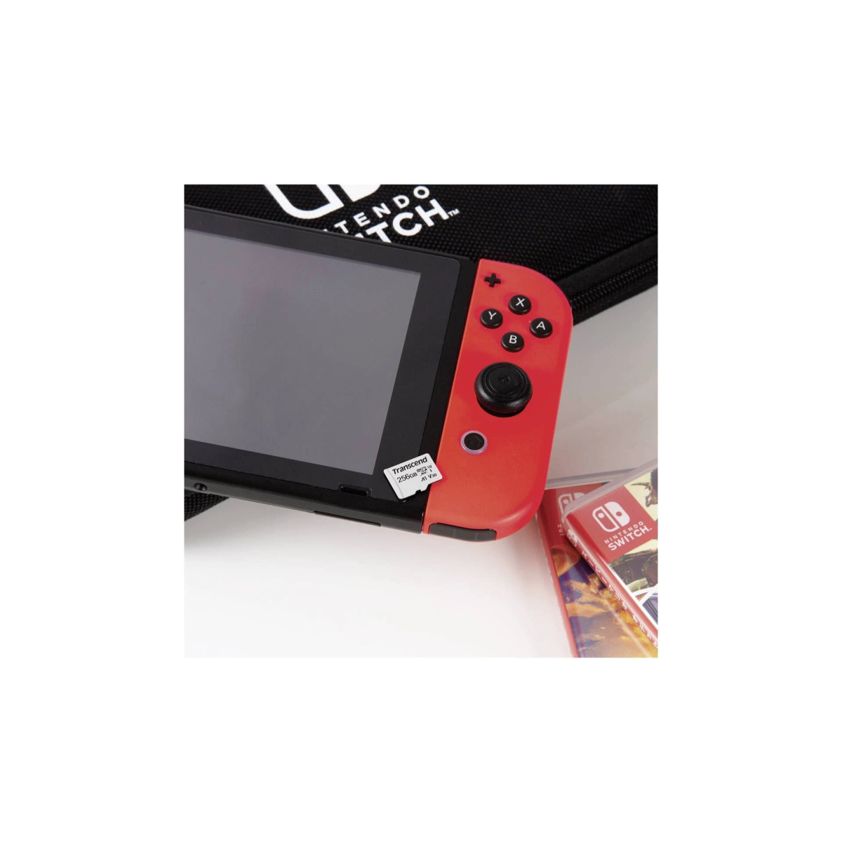 Nintendo Switch mit roten Controllern auf weißer Oberfläche. Box und Hülle sichtbar.
