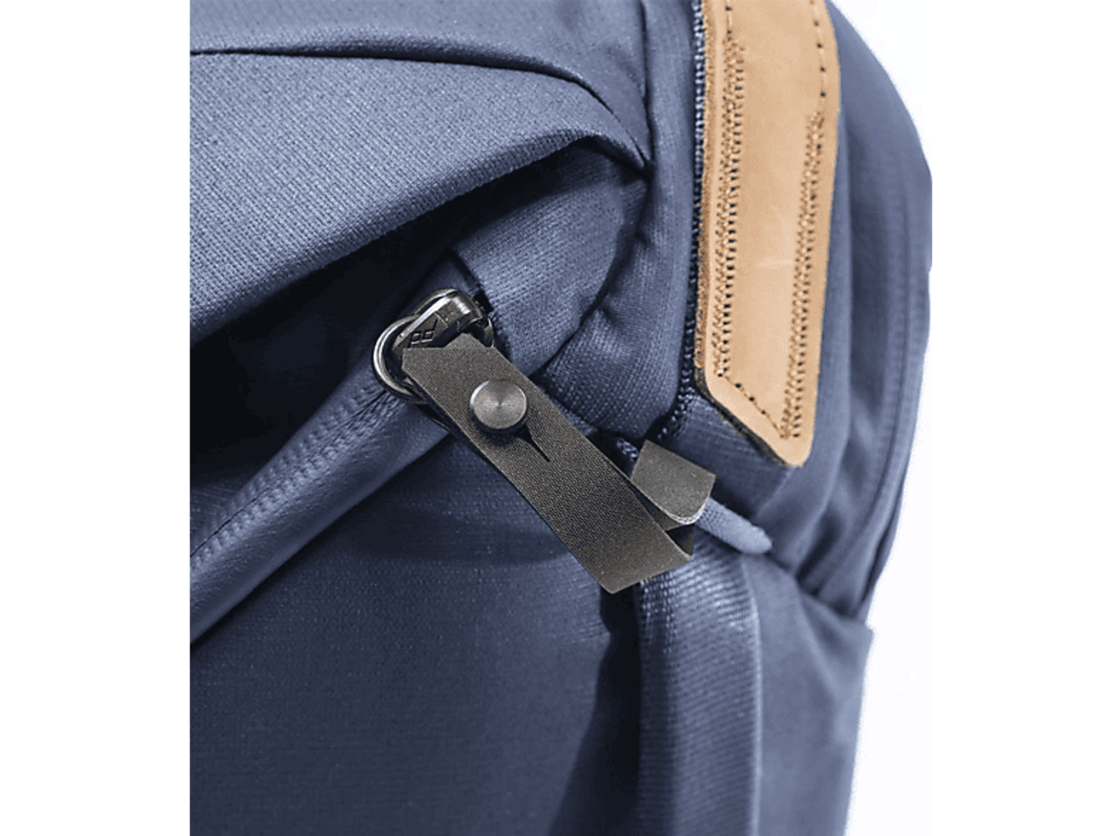 Nahaufnahme eines dunkelblauen Rucksacks mit Lederriemen und Metallreißverschluss.