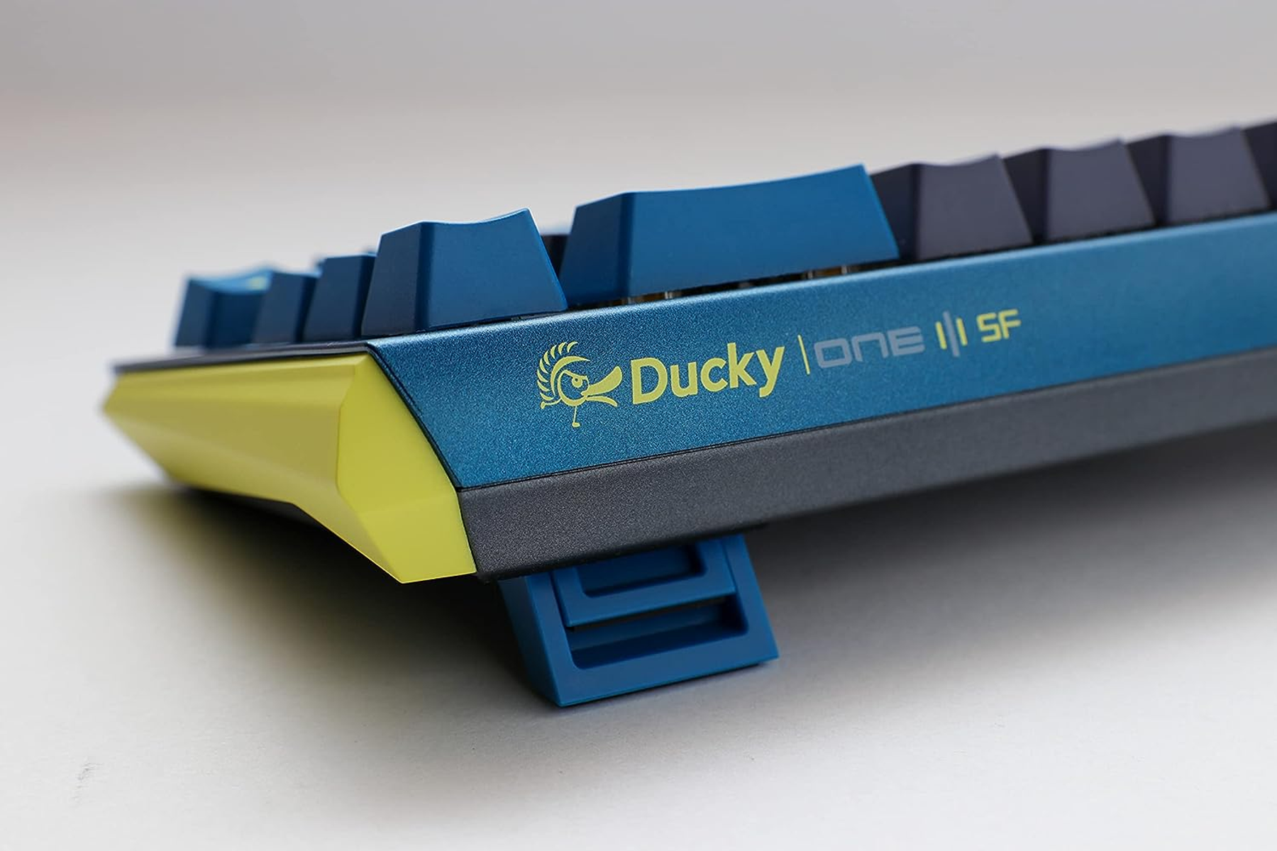 Vista laterale della tastiera blu con logo Ducky, marchio One 3 SF e supporto.