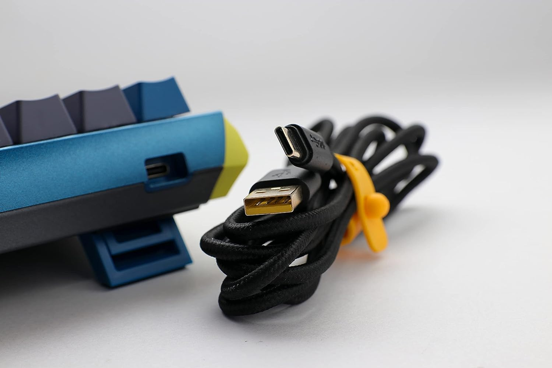 Una tastiera blu e gialla con cavo USB nero.