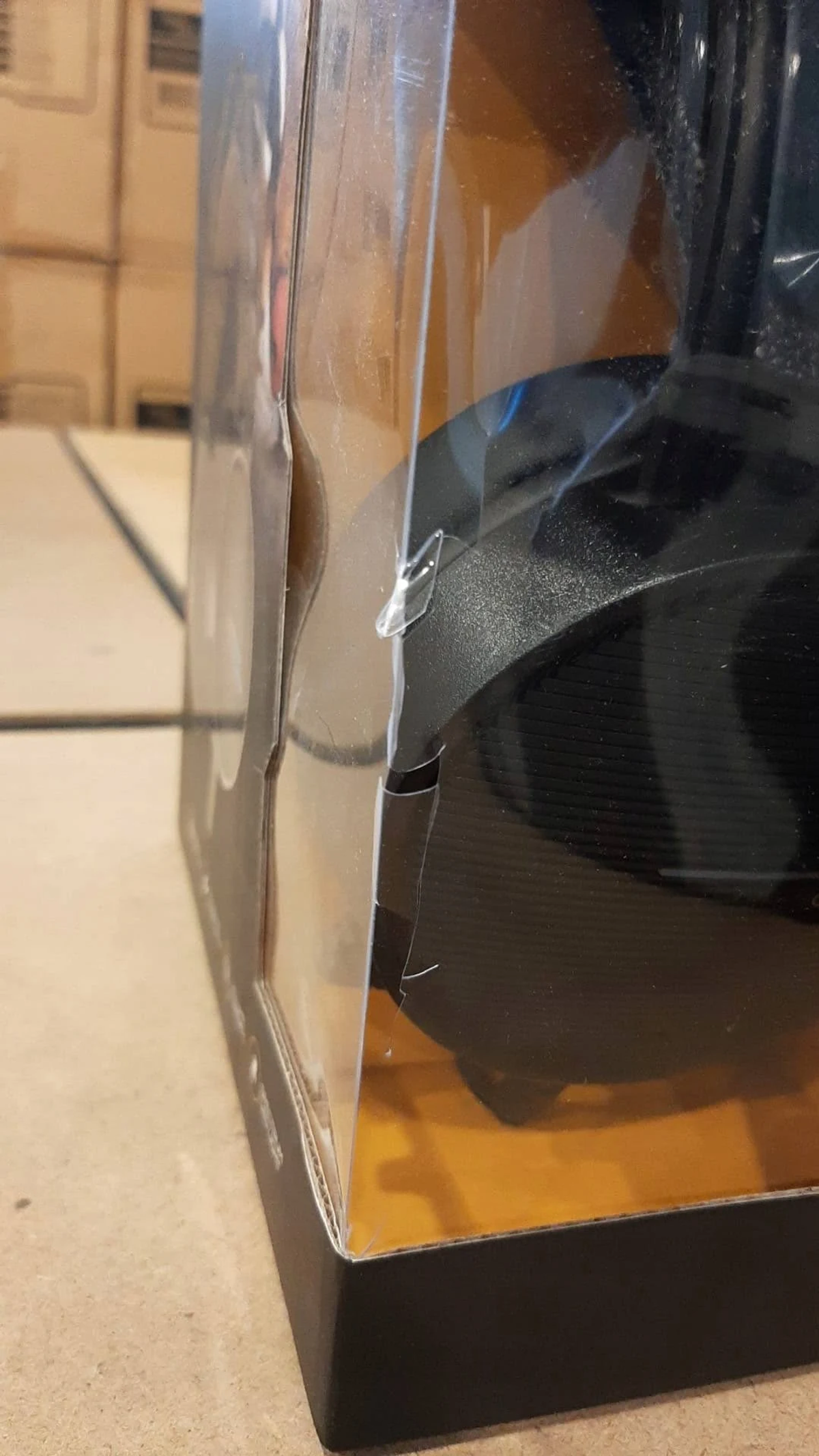 Zestaw słuchawkowy w przezroczystym plastikowym opakowaniu, pokazujący część czarnego zestawu słuchawkowego.