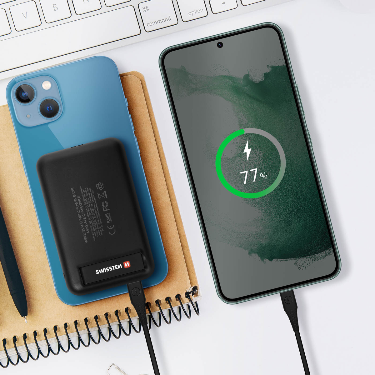 Ein Telefon, das kabellos geladen wird, mit einer schwarzen Powerbank auf einem Notizbuch.