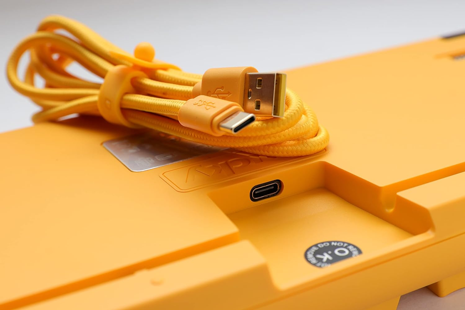 Retro tastiera gialla con porta USB-C, USB dorata e cavo intrecciato giallo.