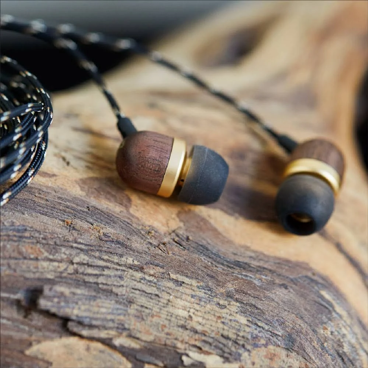 Houten oortelefoons met gouden accenten, zwarte kabel. Op een houten oppervlak.
