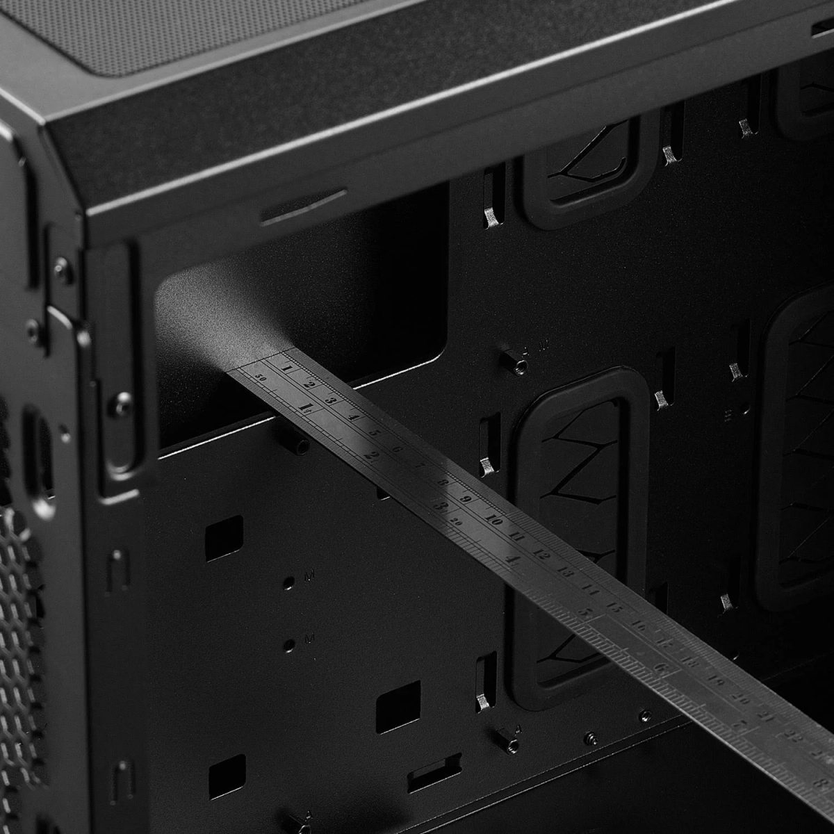 Zwarte binnenkant van de computerkast met een liniaal erin. Toont de interne structuur en afmetingen.