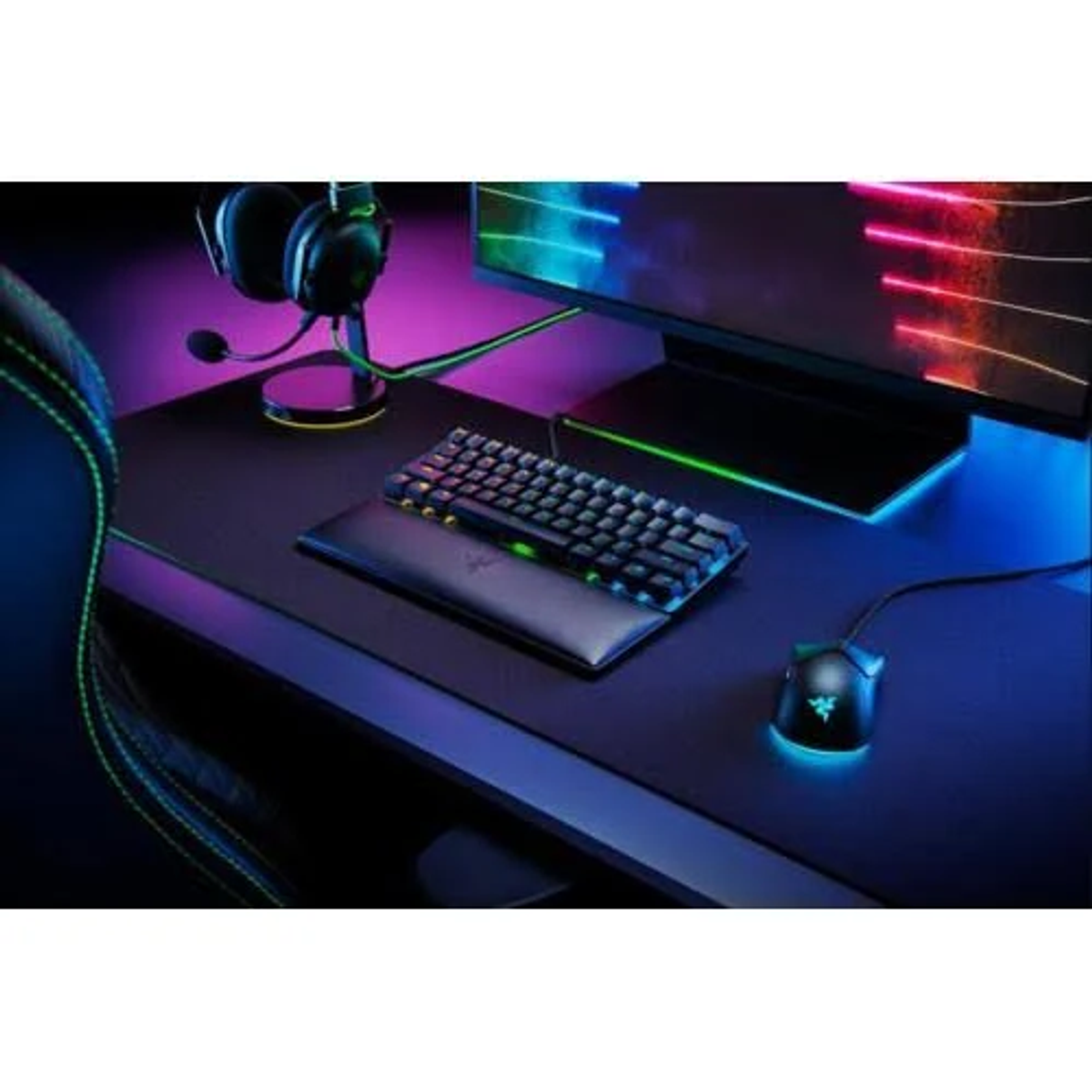 Gaming-Setup mit Tastatur, Maus, Headset und Monitor. Blaues und grünes Licht.