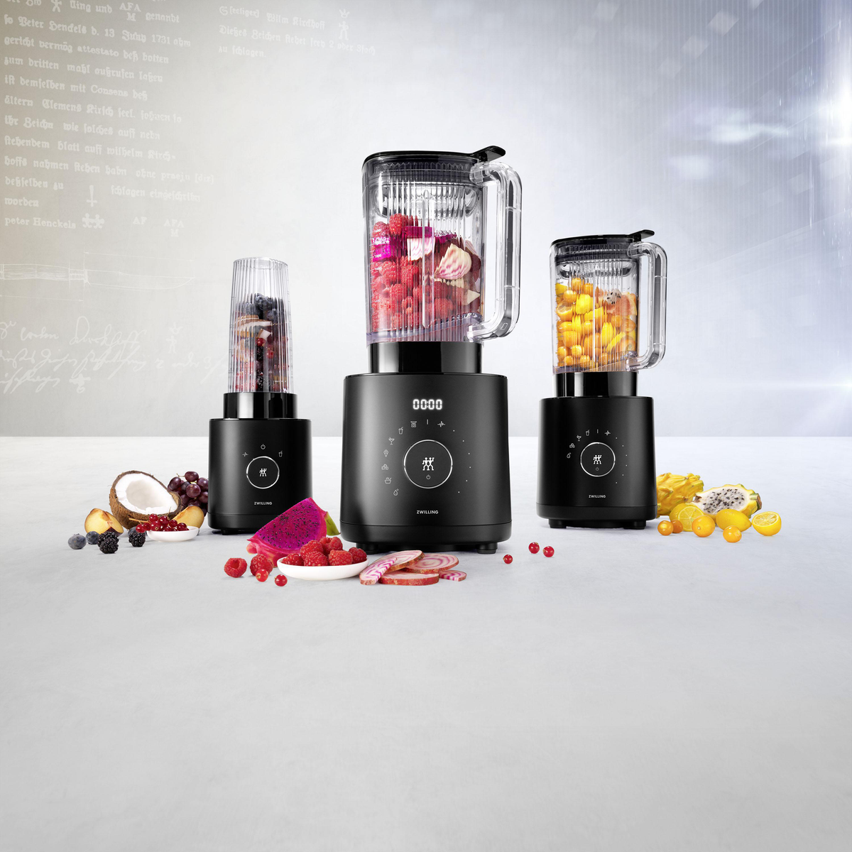 Drei schwarze Mixer mit verschiedenen Früchten. Einer hat Beeren, ein anderer Mango und Früchte.