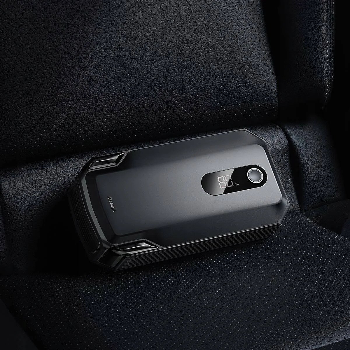 Czarne urządzenie w fotelu samochodowym, wyświetlające procent naładowania.