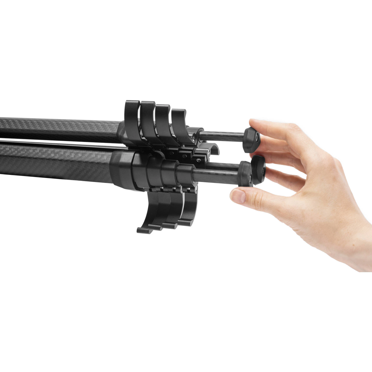 Dłoń osoby łącząca części czarnego statywu z włókna węglowego.