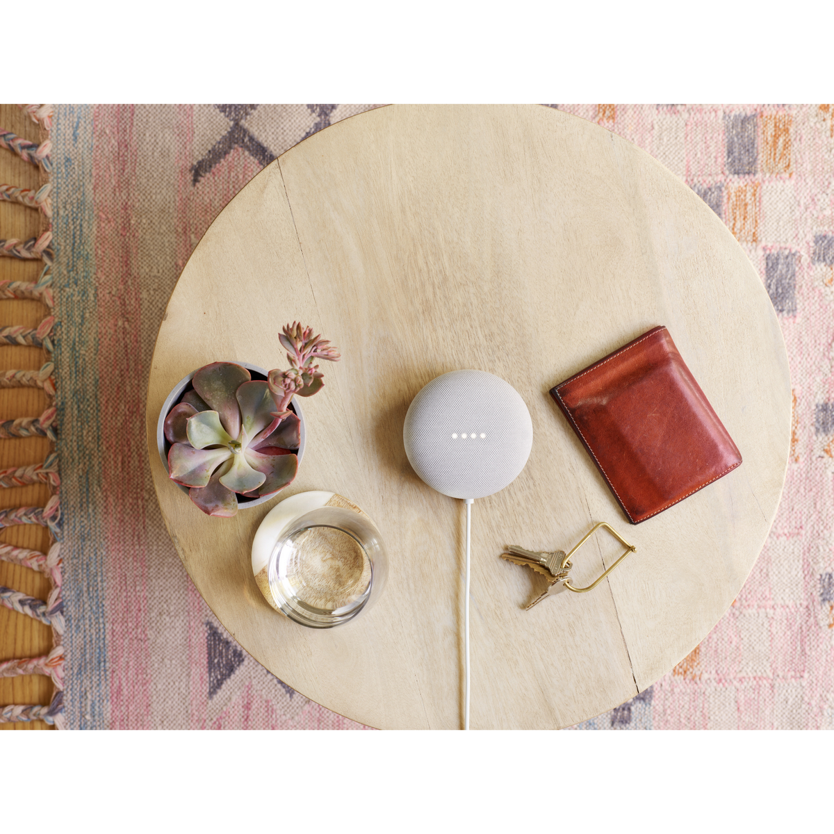 Widok z góry na Google Nest Mini, klucze, portfel i sukulent na stole.