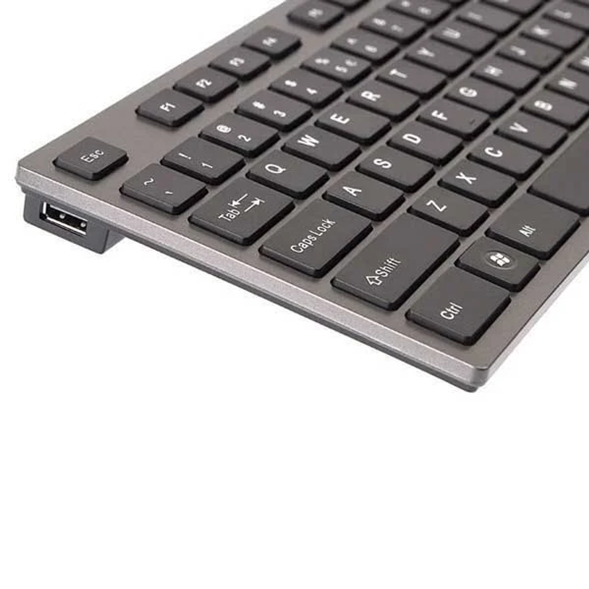 Primo piano di una tastiera grigia con tasti neri e porta USB sul lato.