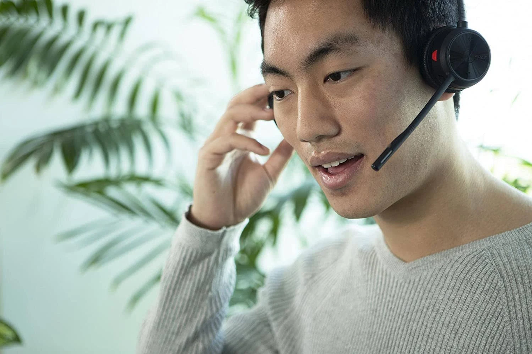 Homme portant un casque, en appel vidéo. Plantes vertes en arrière-plan.