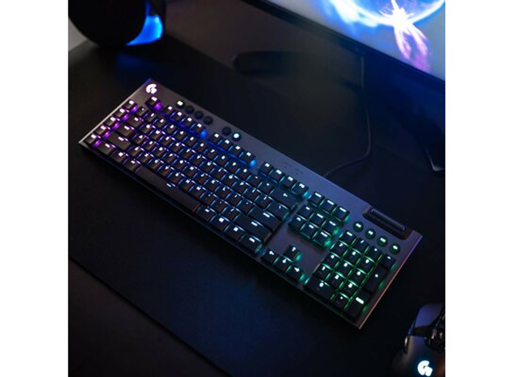 Black keyboard with colorful lights. Dark background. Mouse is on the right.