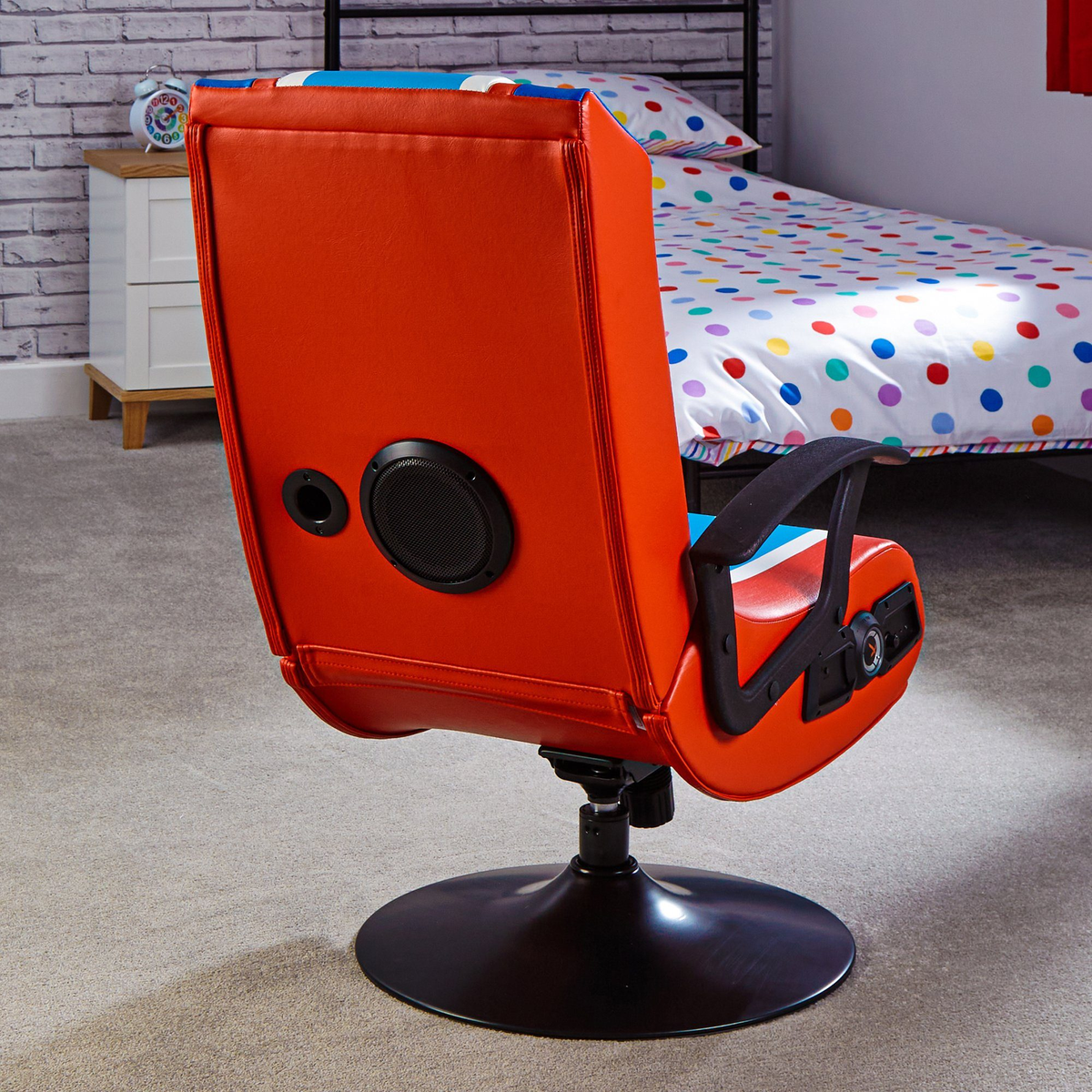 Roter und schwarzer Gaming-Stuhl mit Lautsprecher. Schlafzimmer mit Bett im Hintergrund.