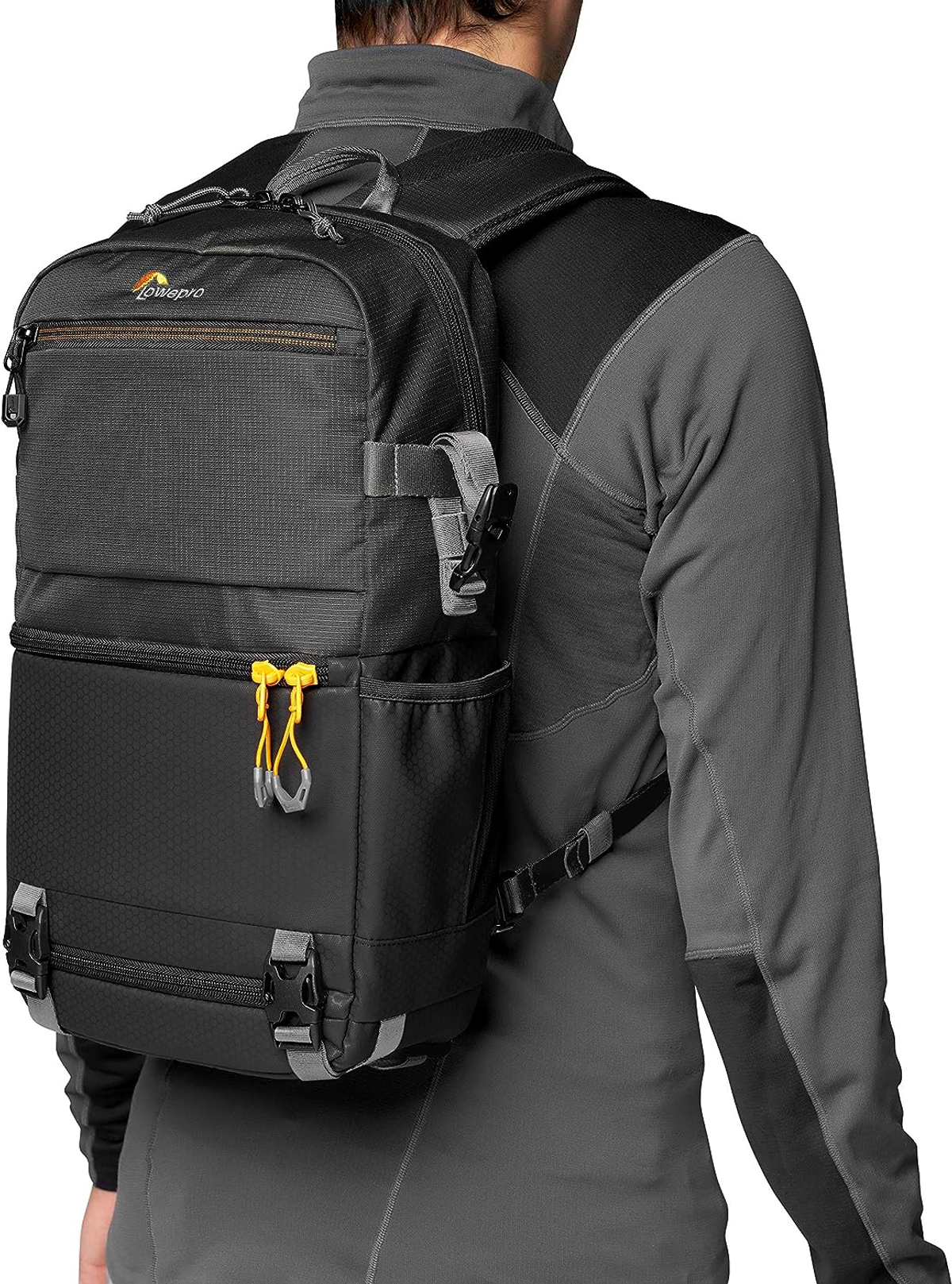 Eine Person mit grauer Jacke und schwarzem LowePro-Rucksack.