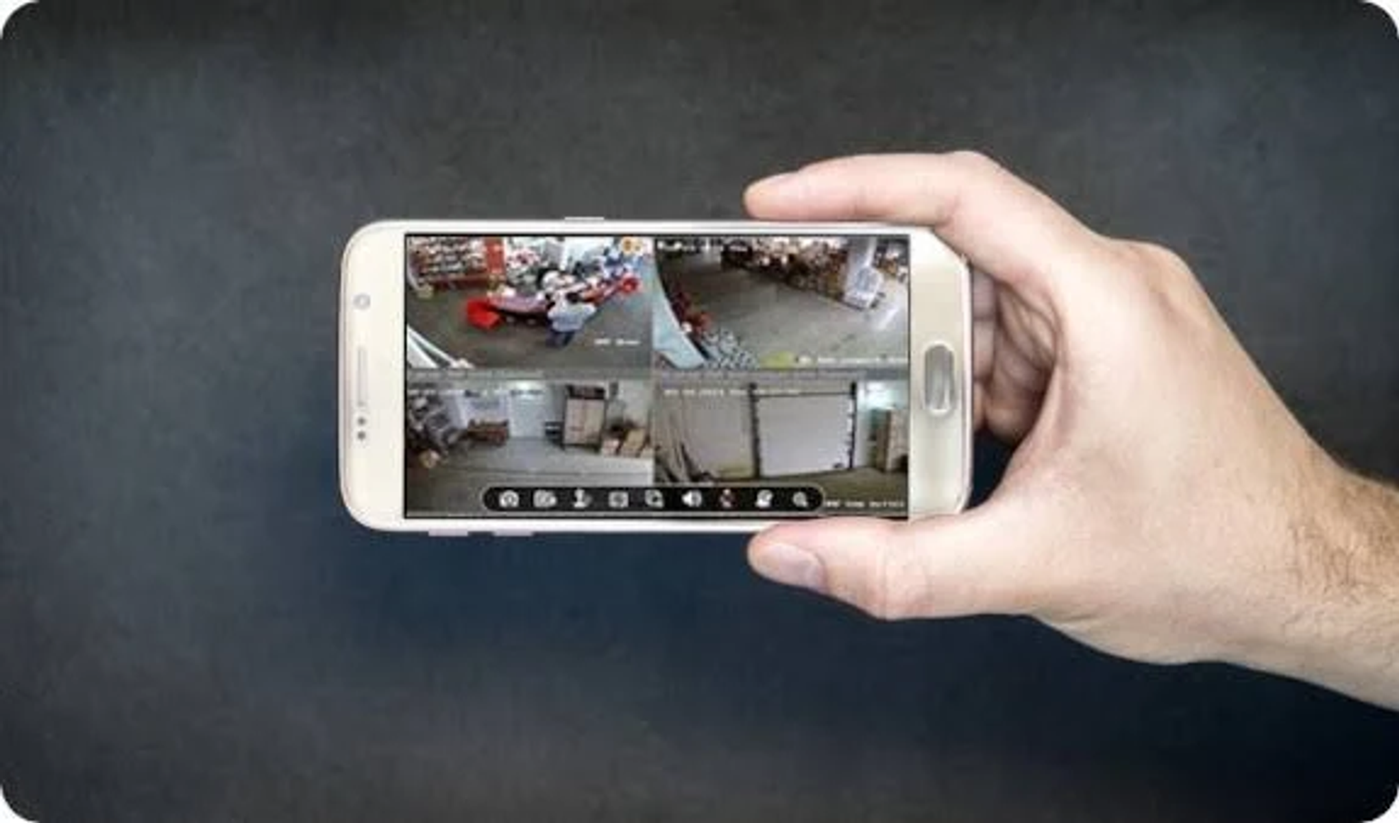 Dłoń trzymająca telefon z czterema widokami z kamery sklepu.