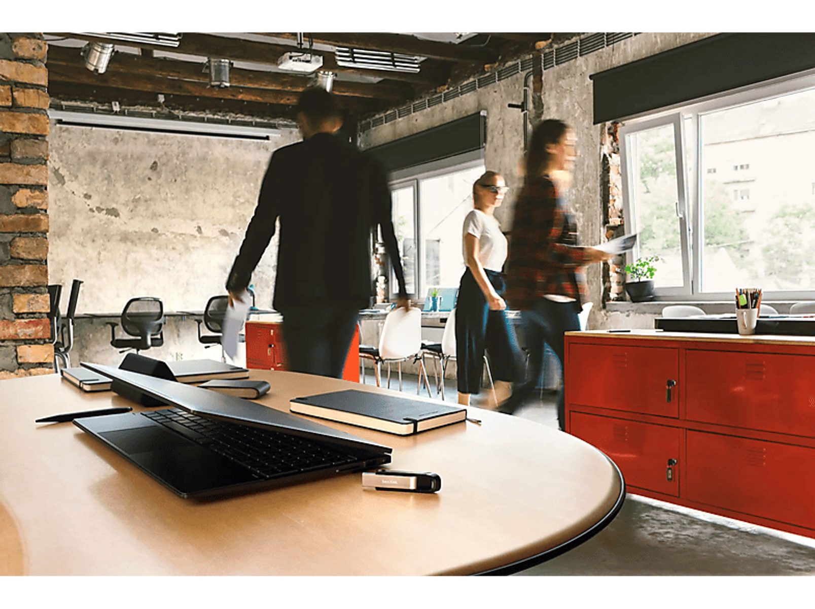 Scena biurowa z ludźmi przechodzącymi obok stołu.