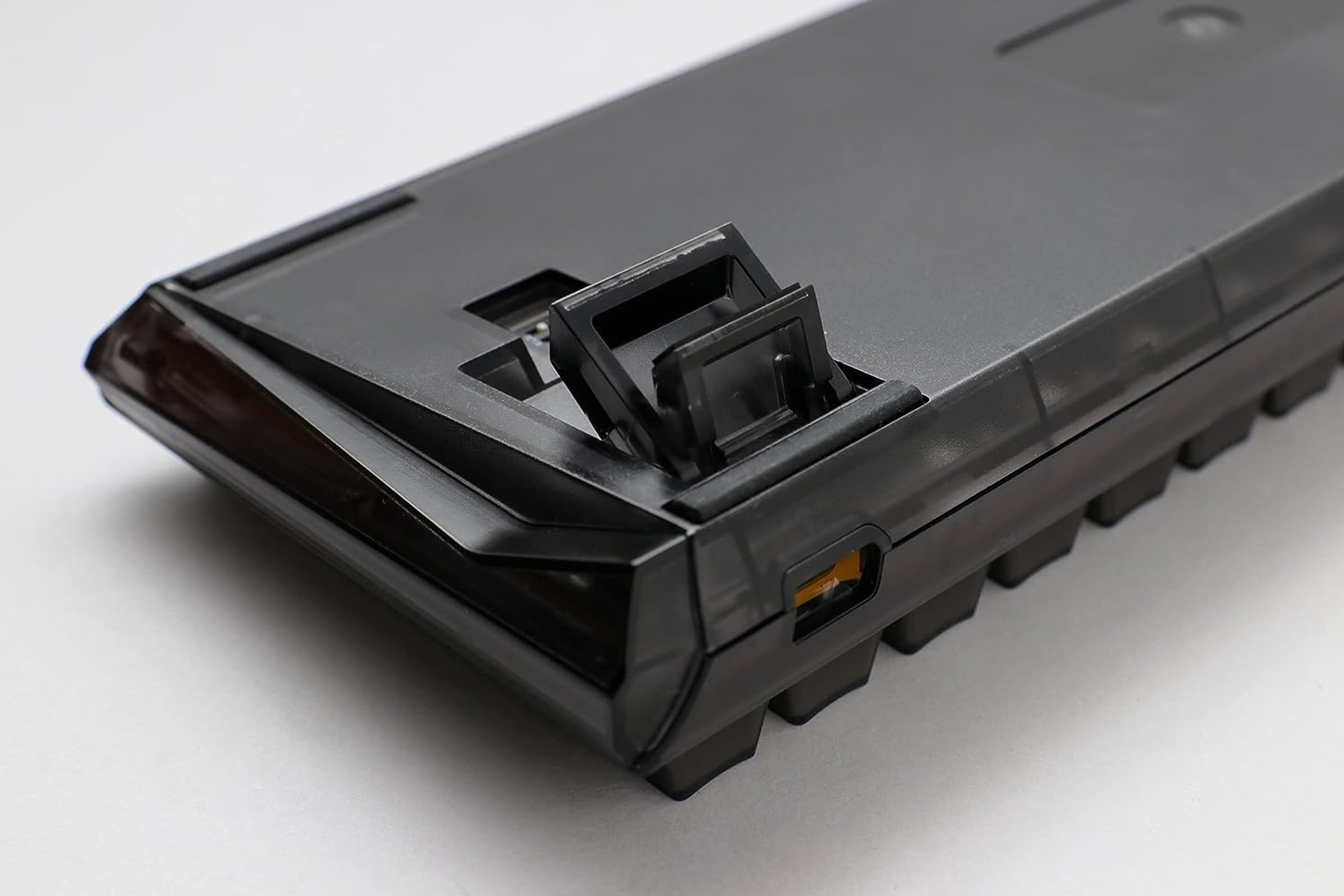 Czarna podstawa klawiatury z otwartymi nóżkami. Pokazuje port USB i czarny korpus.