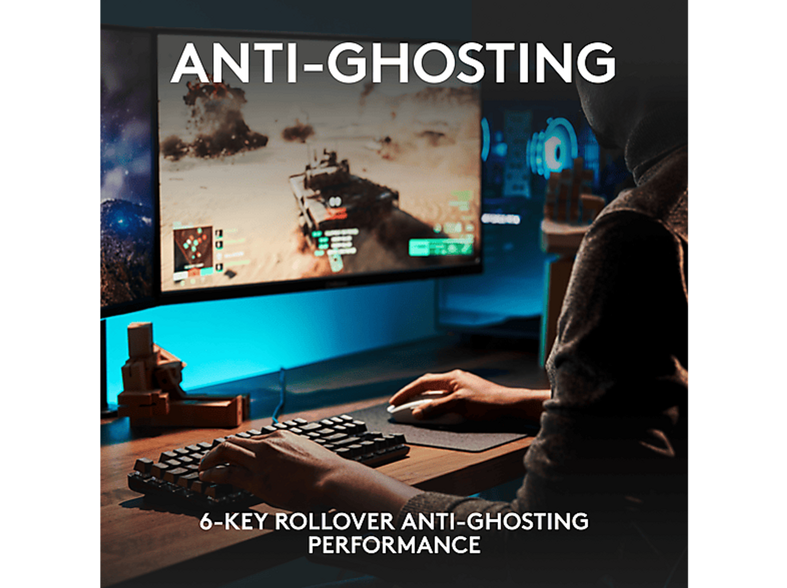 Osoba gra w grę na komputerze. Scena zawiera klawiaturę i dwa monitory. Tekst: Anti-Ghosting.