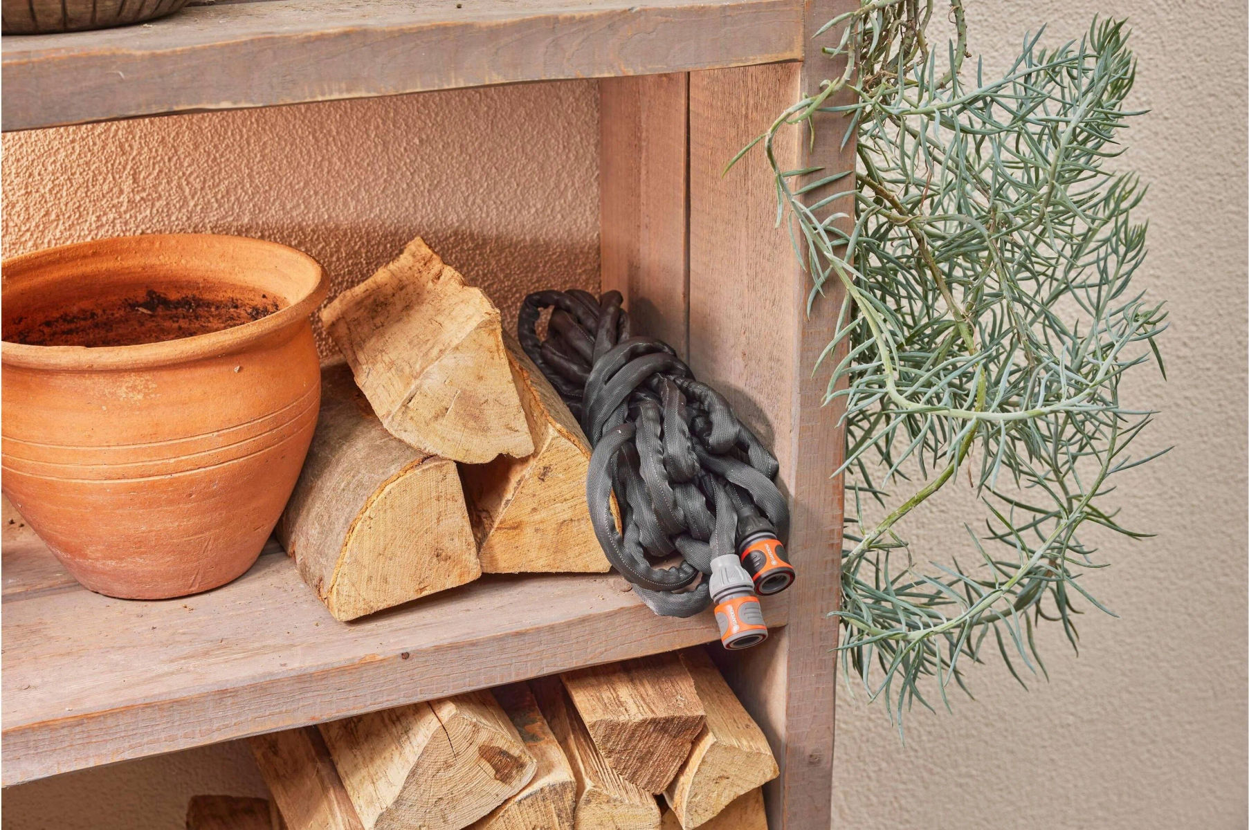 Drewniane półki z drewnem opałowym, donicą z terakoty i zwiniętym szarym wężem.