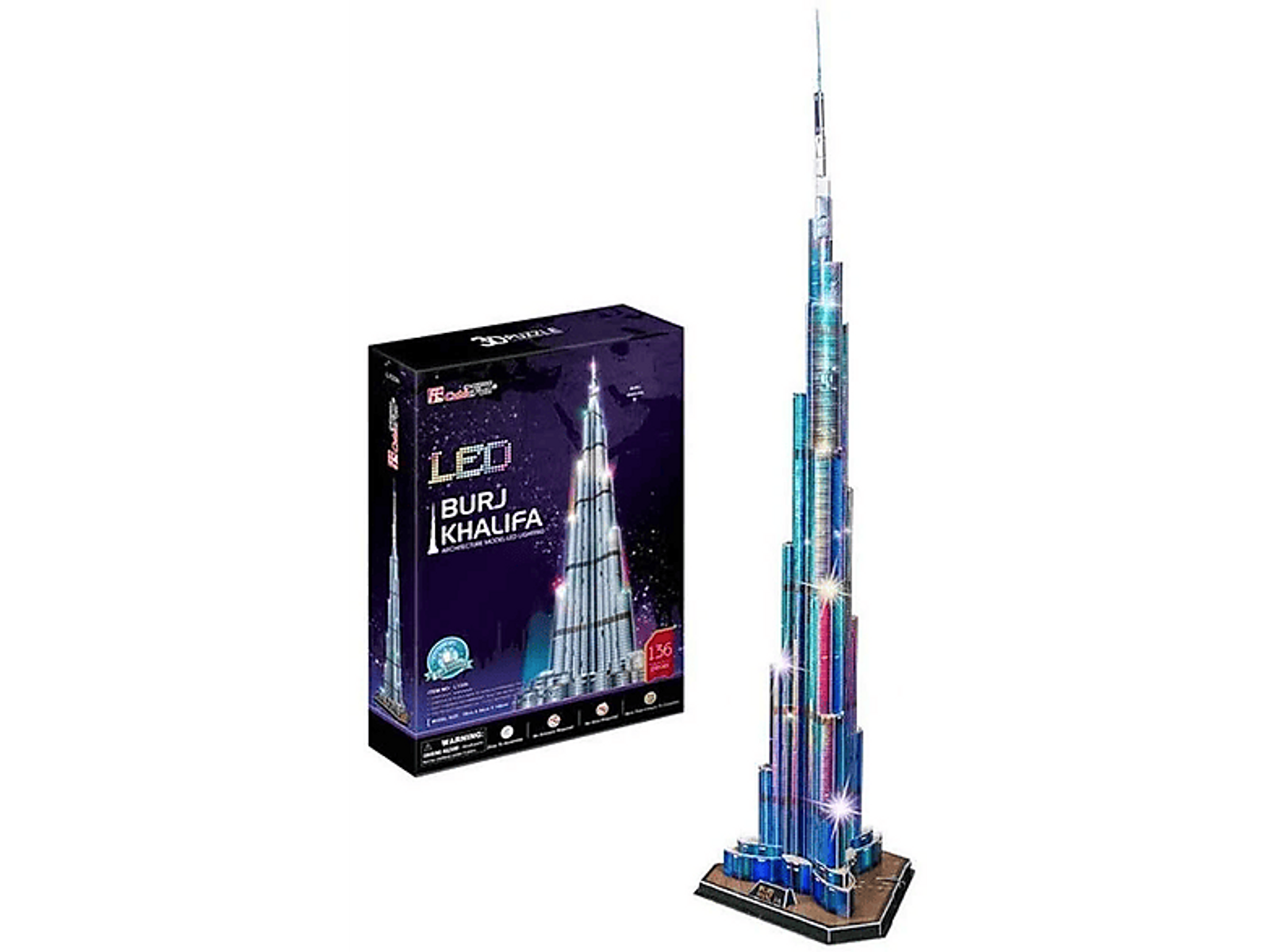 Puzzle 3D Burj Khalifa. Model stoi obok pudełka. Wieża jest podświetlona niebieskimi i zielonymi światłami.