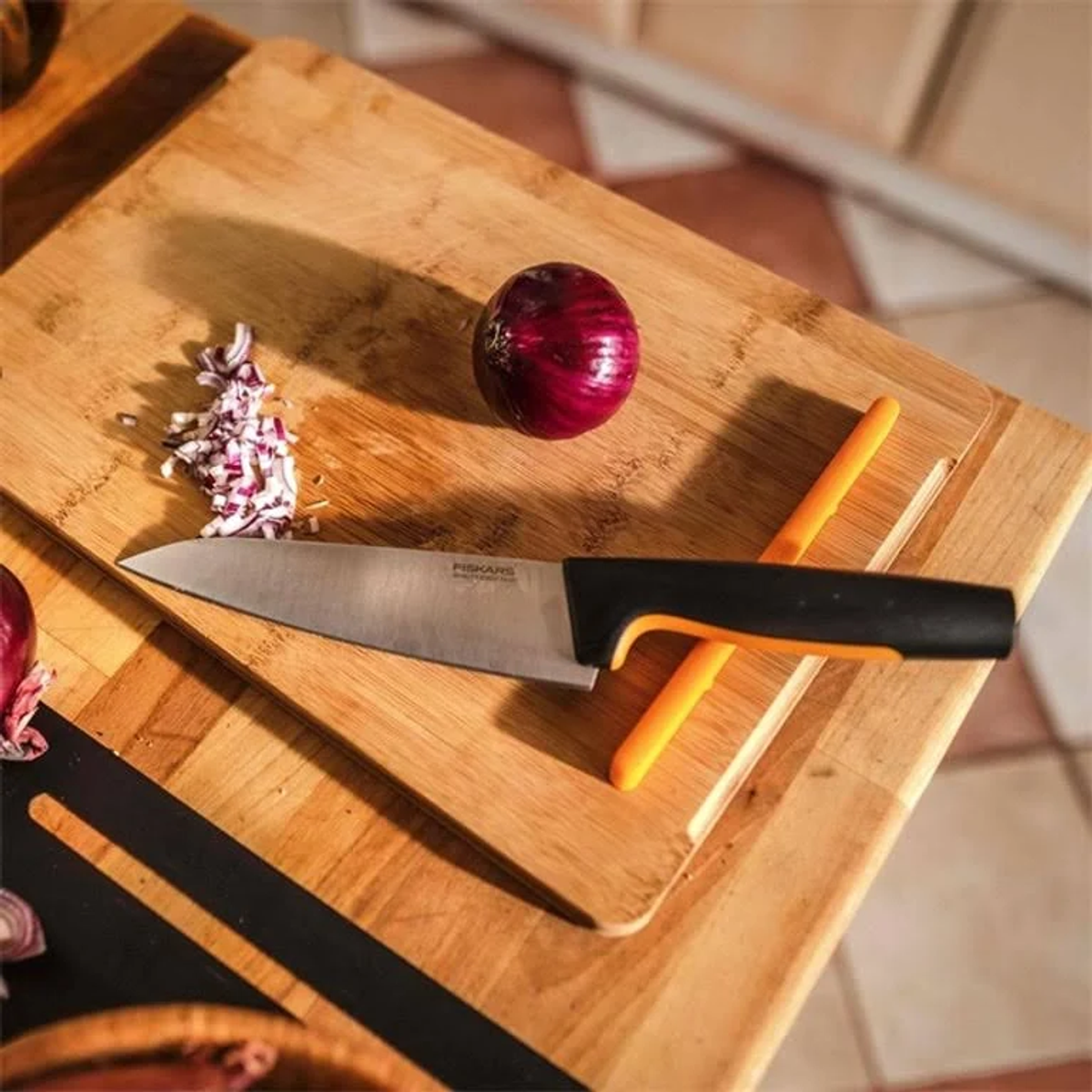 Nóż na drewnianej desce do krojenia. Posiekana czerwona cebula i cała widoczne.