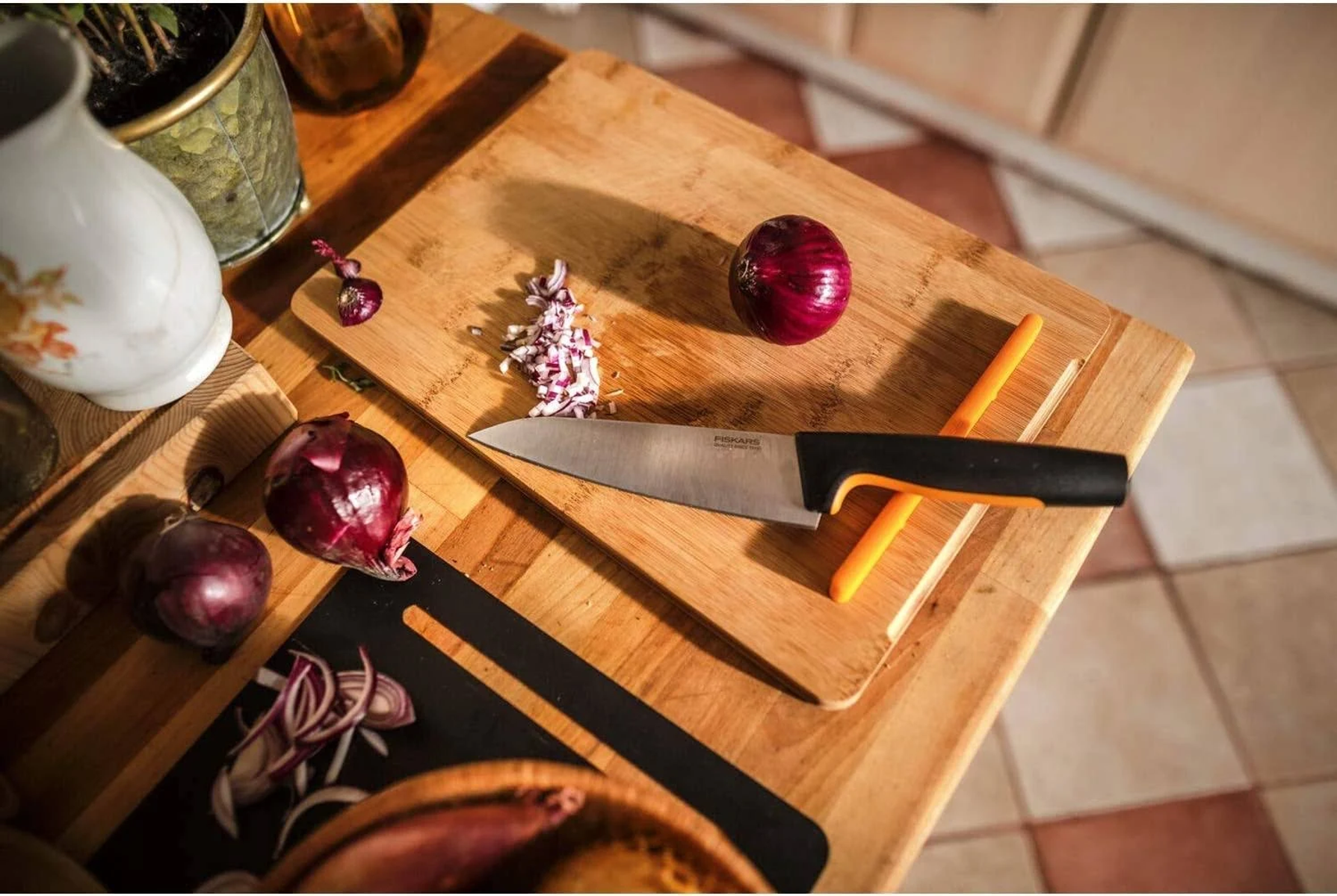 Drewniana deska do krojenia z nożem i pokrojoną cebulą. Obecne są również dwie czerwone cebule.