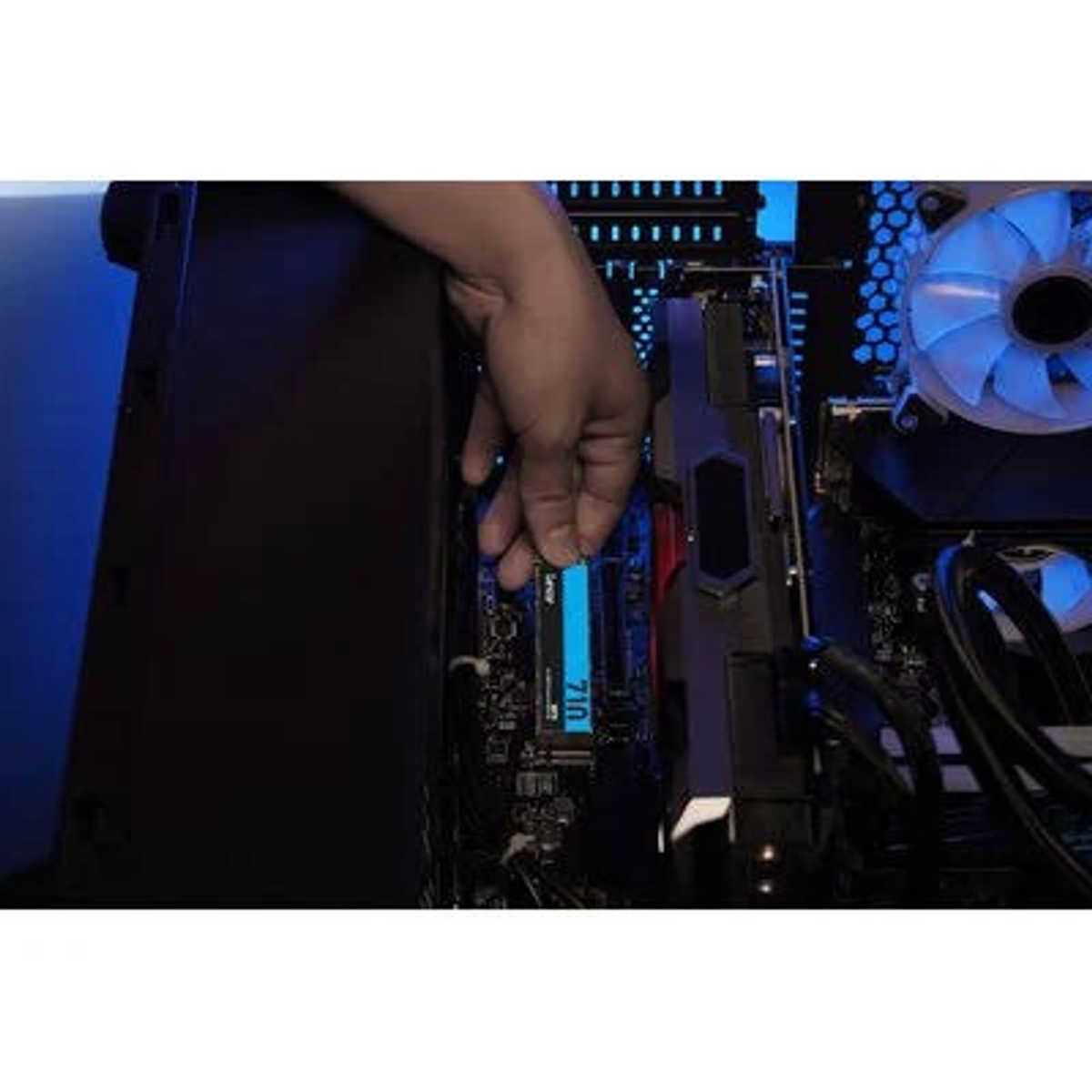 Ręka instalująca niebieski moduł RAM w płycie głównej komputera, w ciemnej obudowie.