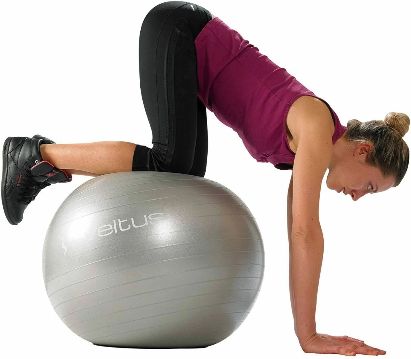 Donna su una palla da ginnastica grigia che fa un plank. Indossa abiti da allenamento.