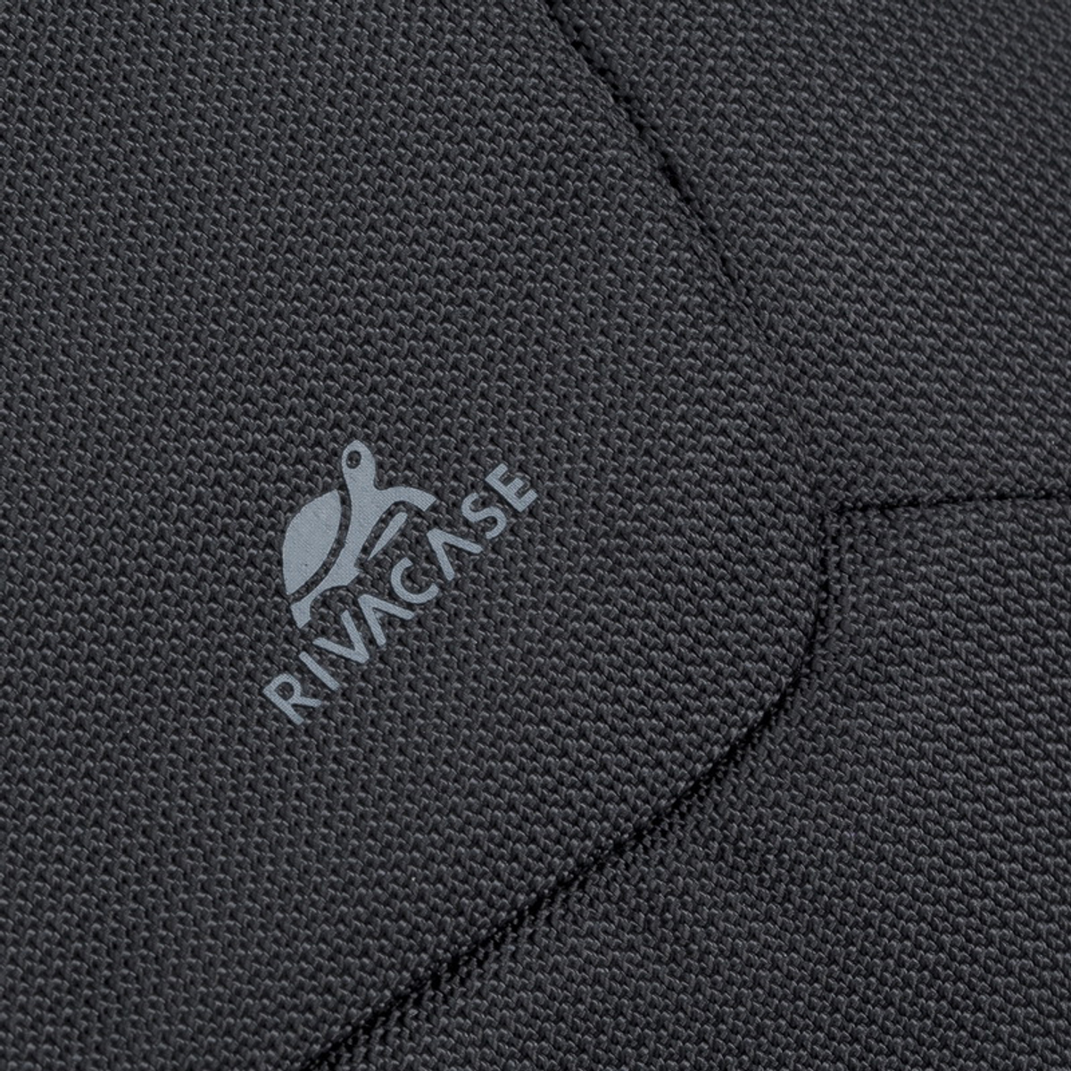 Nahaufnahme eines schwarzen Stoffes mit grauem "RIVACASE"-Logo. Der Stoff hat ein strukturiertes Muster.