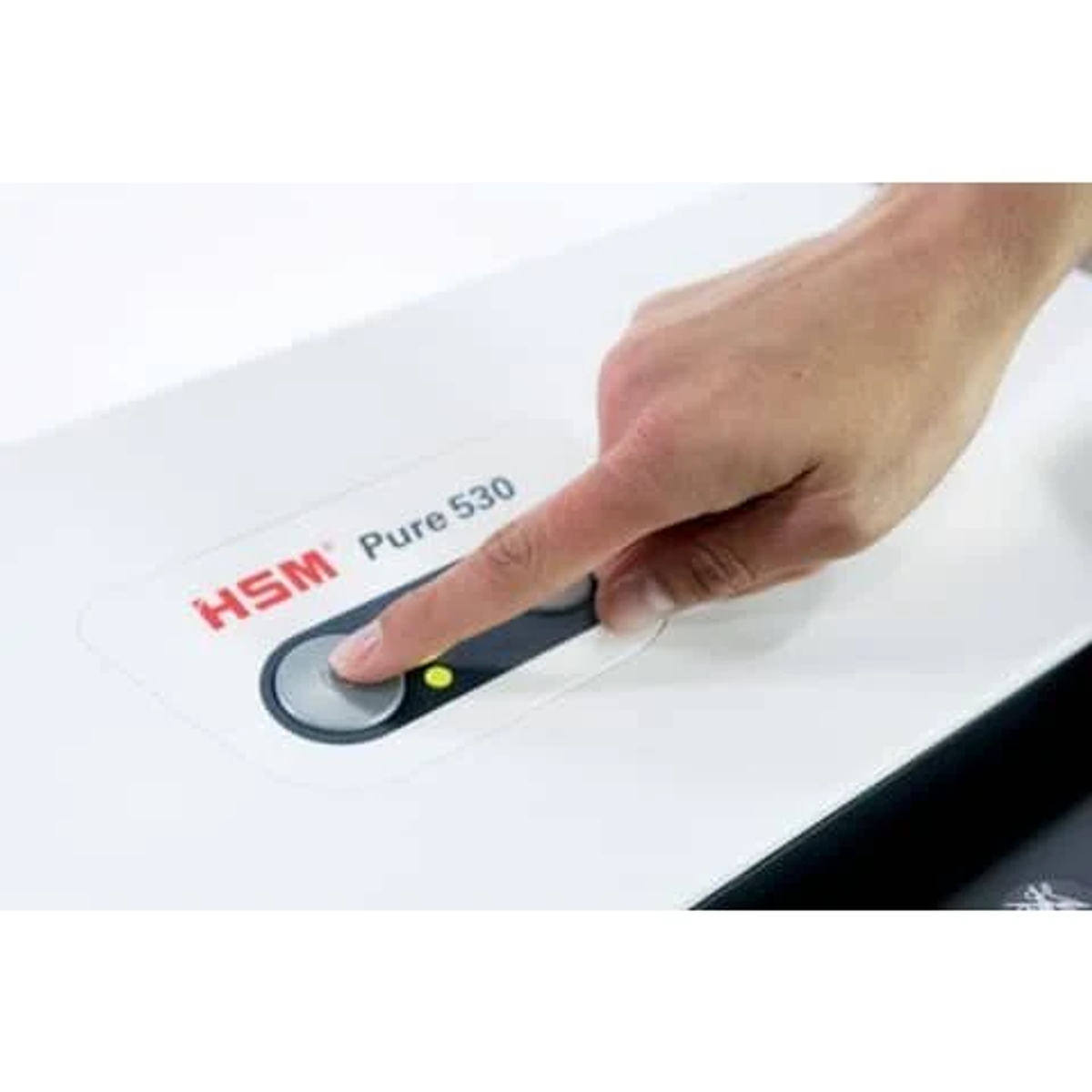 Eine Hand drückt auf eine Taste eines weißen HSM Pure 530 Aktenvernichters. Die Taste leuchtet grün.