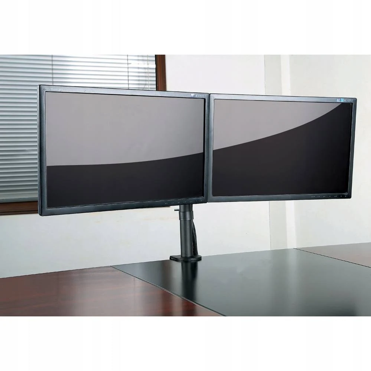 Zwei schwarze Computermonitore auf einem Schreibtisch. Sie sind durch einen schwarzen Ständer verbunden.