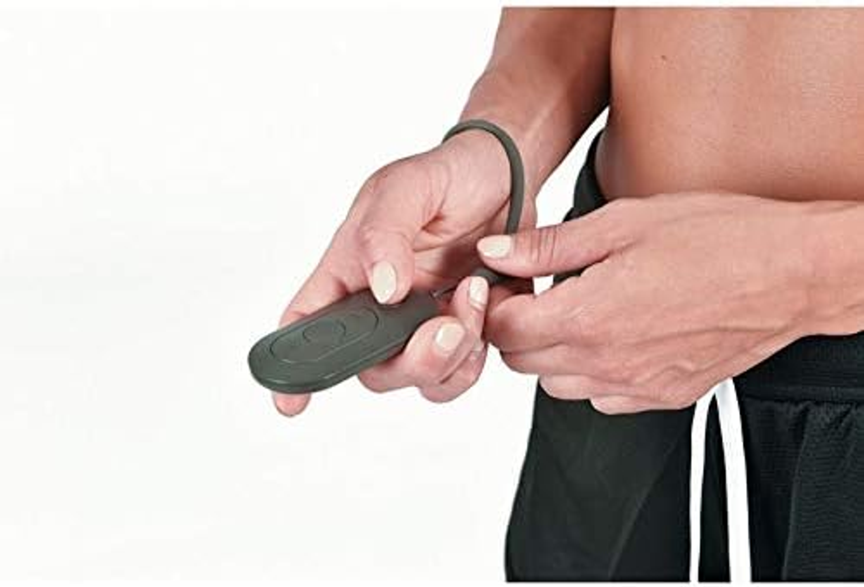 Person's hands holding a small gray device with a wrist strap.