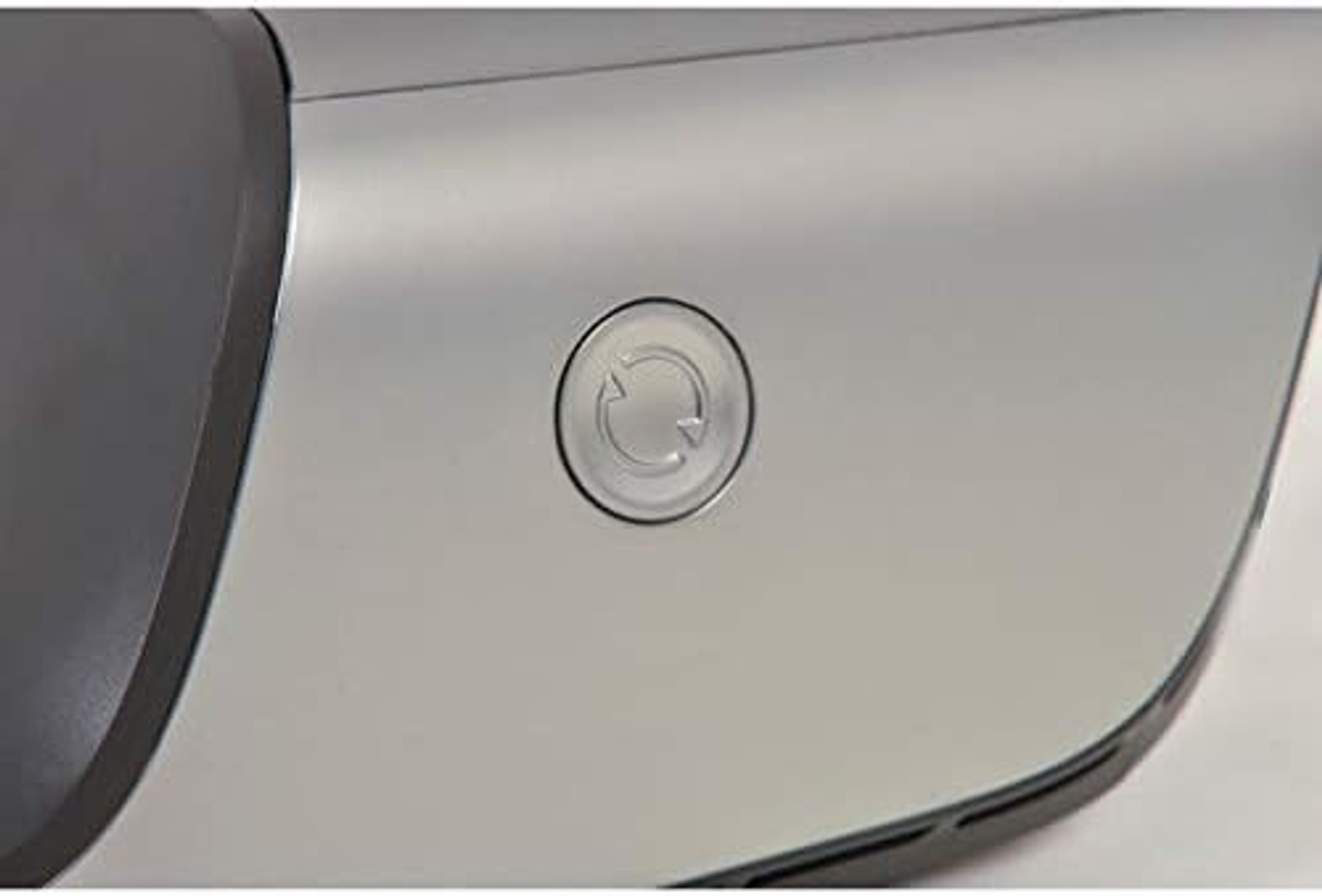 Close-up of a silver device with a circular button that has a recycling symbol on it.