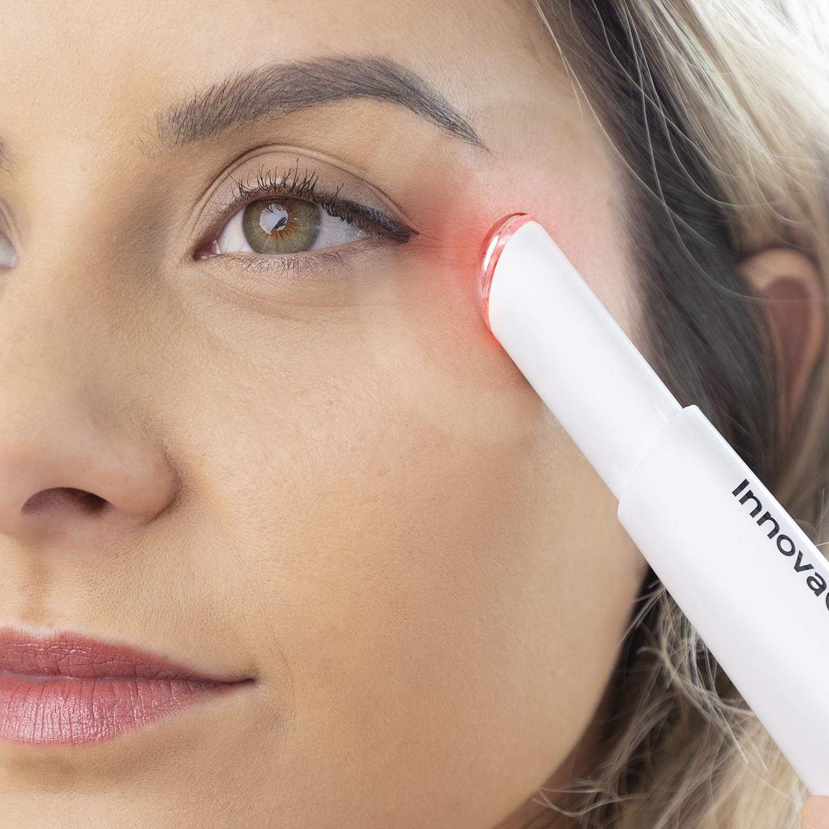 L'area degli occhi di una donna trattata con un dispositivo bianco che emette luce rossa.
