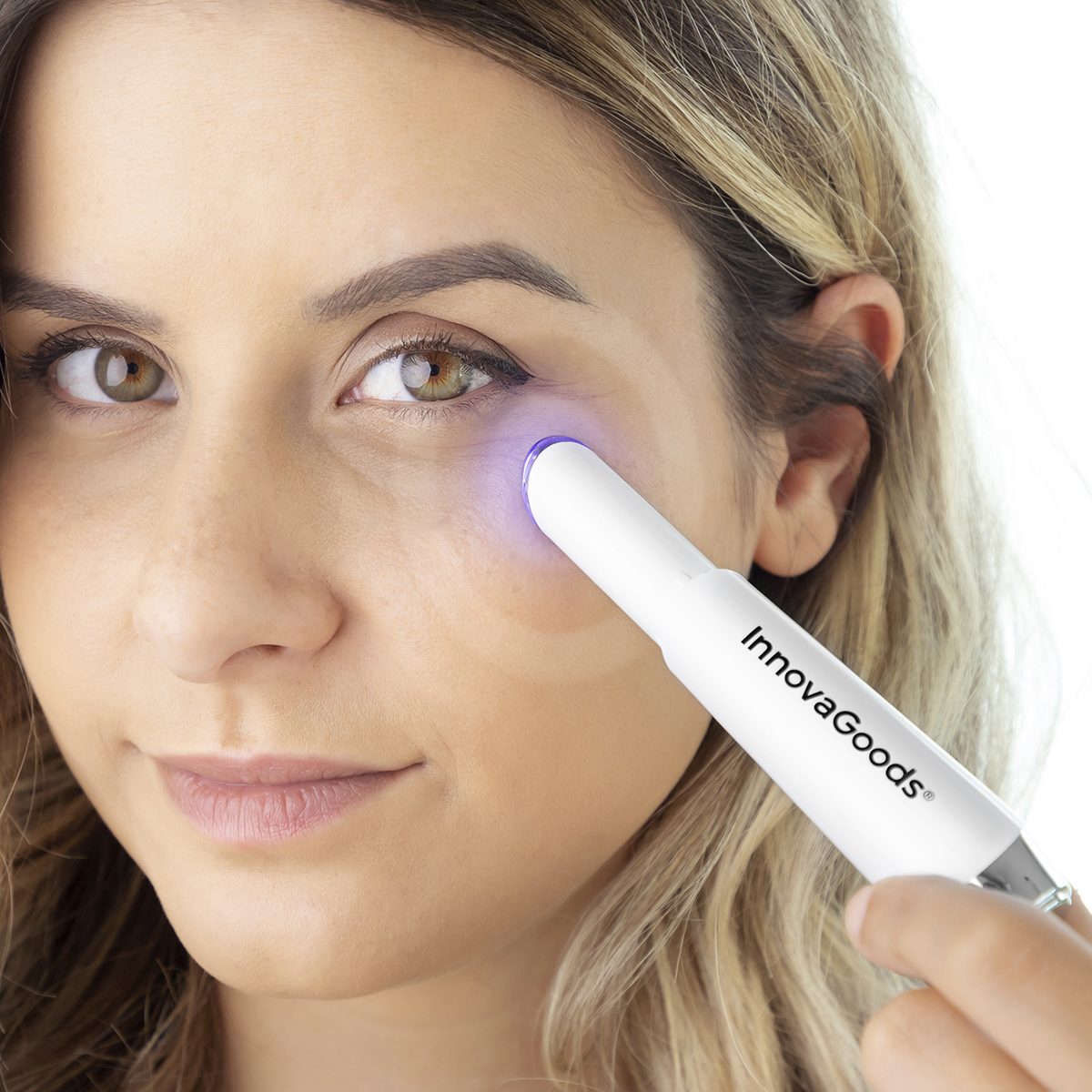 Donna usa un dispositivo di bellezza InnovaGoods bianco sull'occhio.