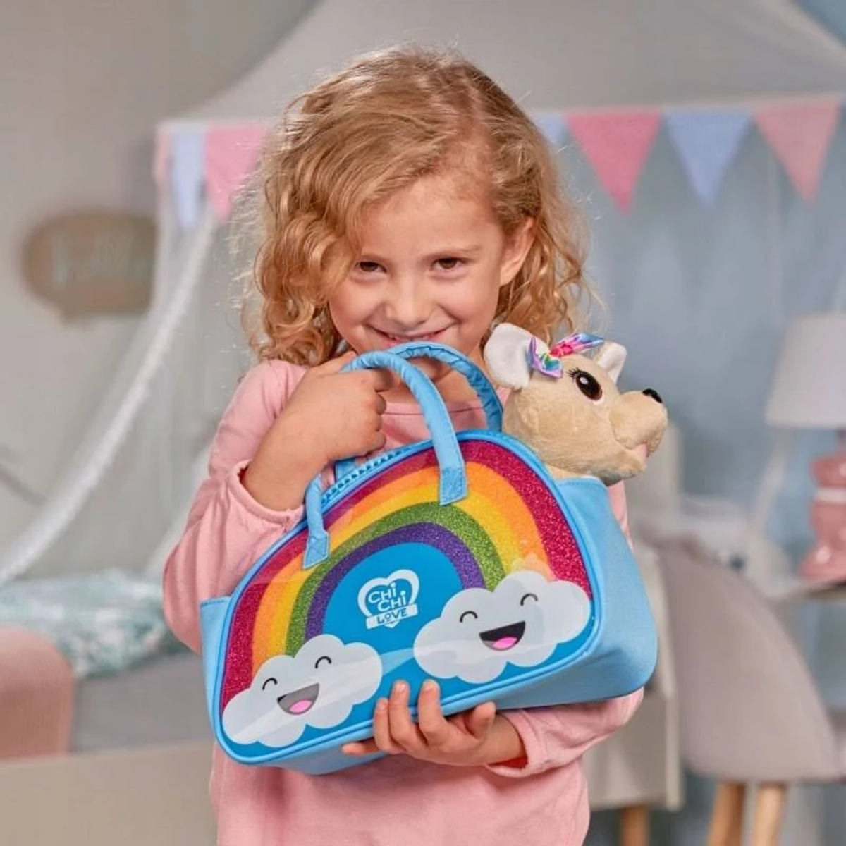 Niña pequeña sosteniendo un bolso azul con un arcoíris y un perro de peluche.