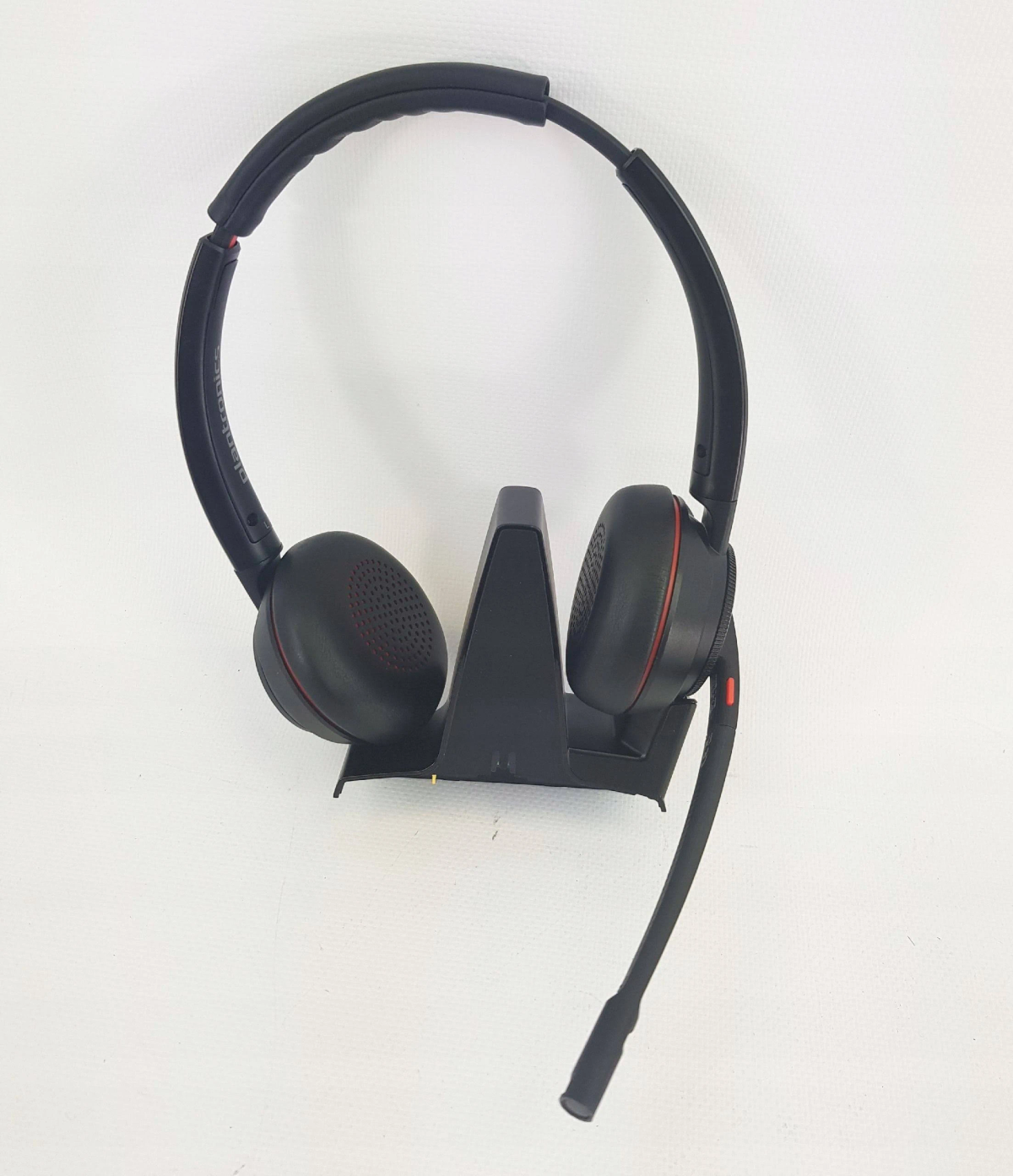 Schwarzes Headset mit Mikrofon und Ladestation. Das Headset hat rote Akzente.