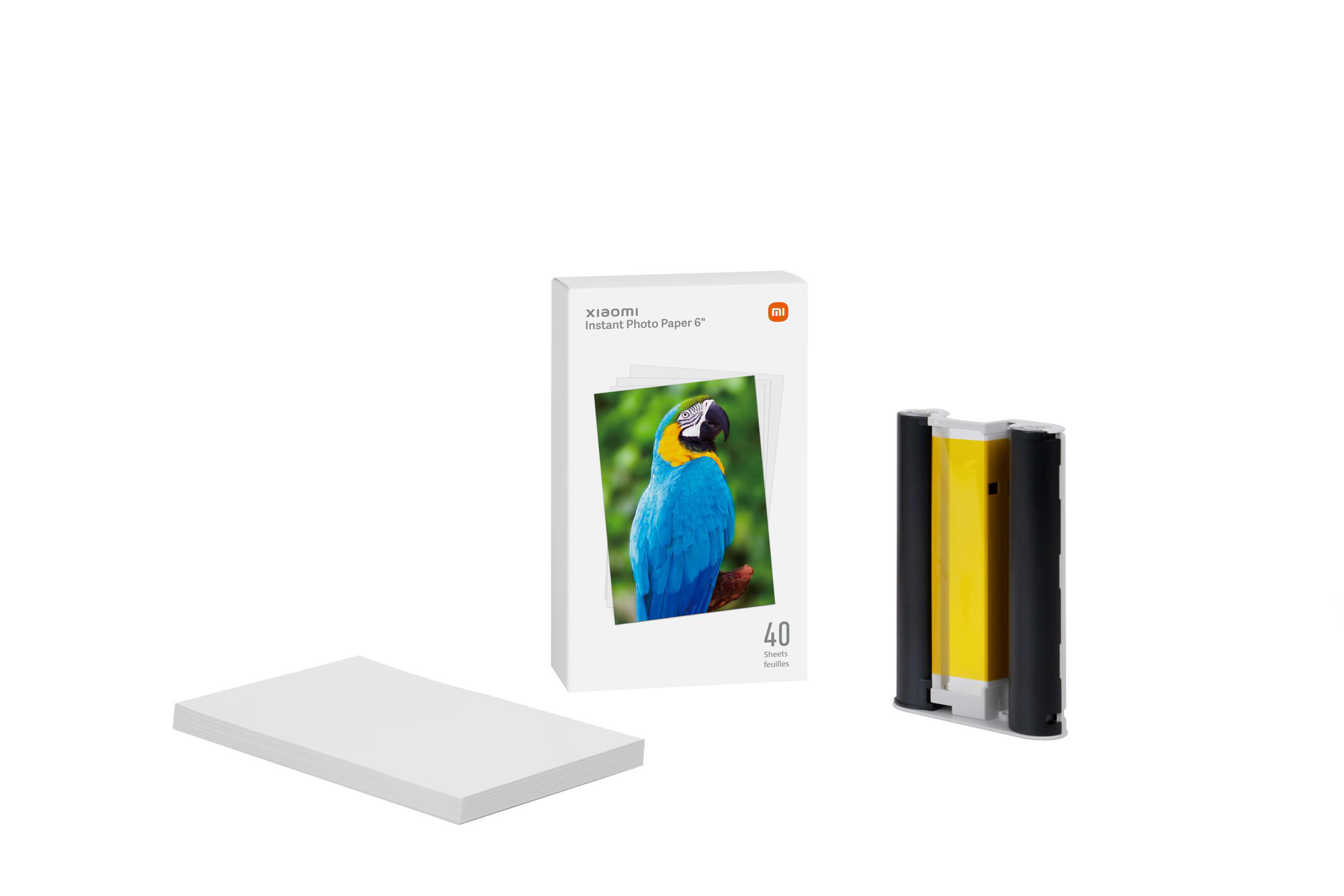 Pudełko Xiaomi Instant Photo Paper 6*, stos papieru i wkład atramentowy na białym tle.