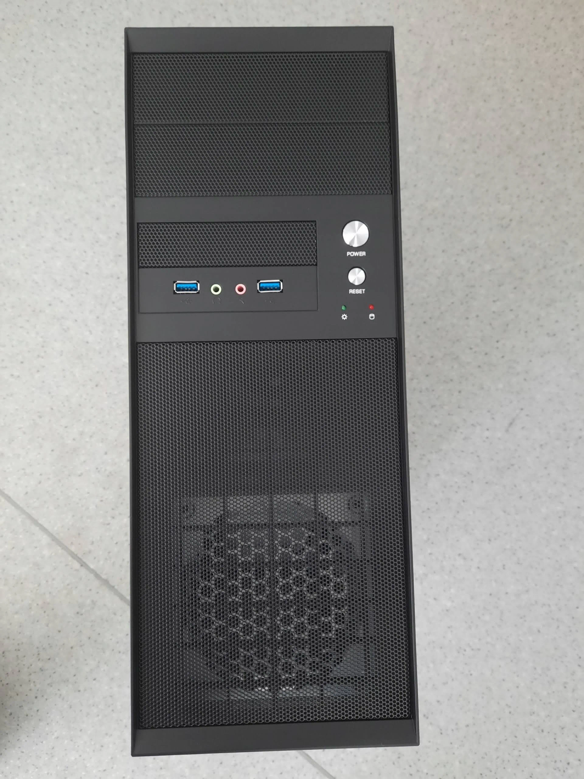 Czarna obudowa komputera z portami z przodu, przyciskami zasilania i resetowania. Ma siatkowy przód i przycisk zasilania.